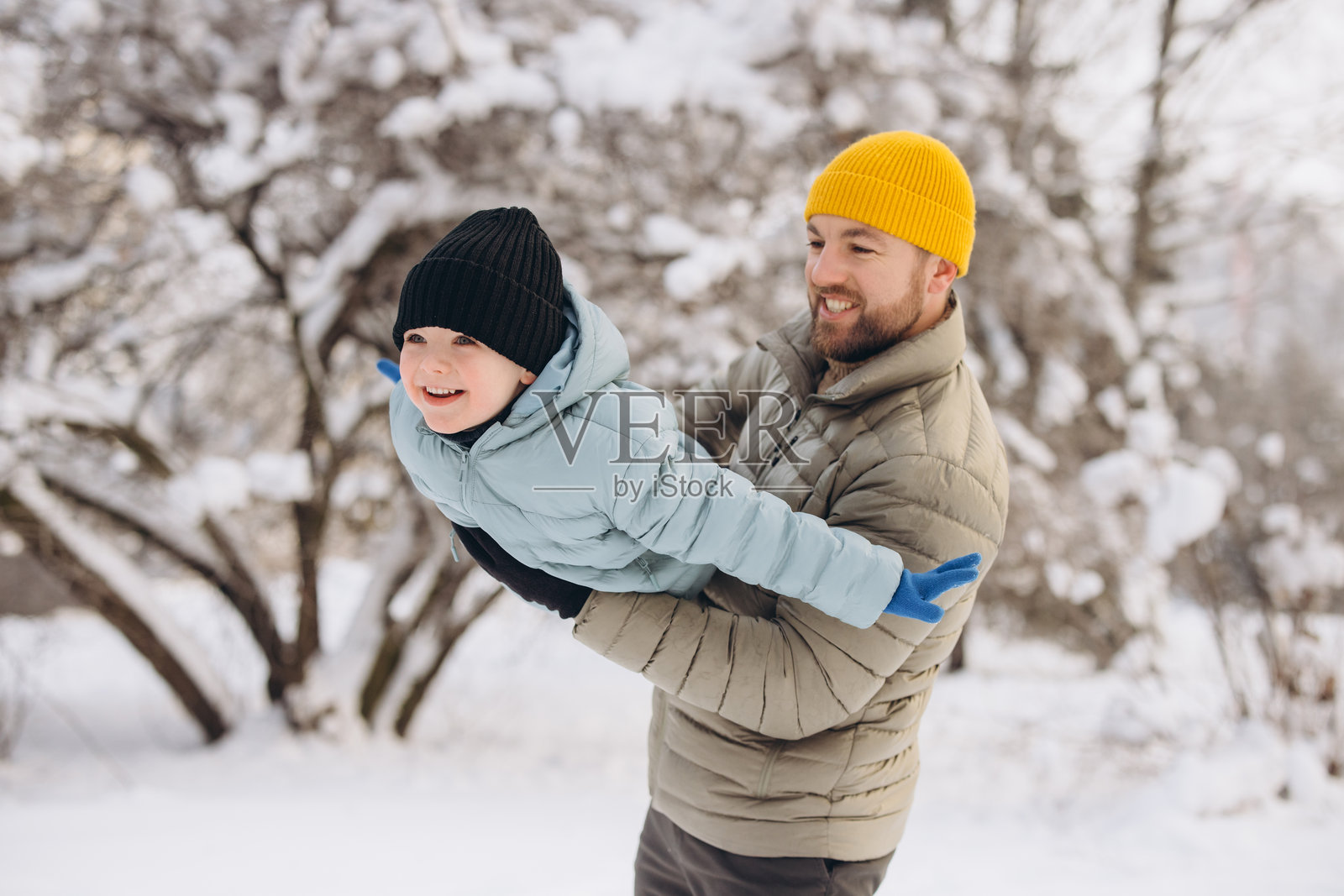 父亲在冬天的雪地里和快乐的儿子玩耍，享受寒冷天气下的户外家庭亲子时光照片摄影图片