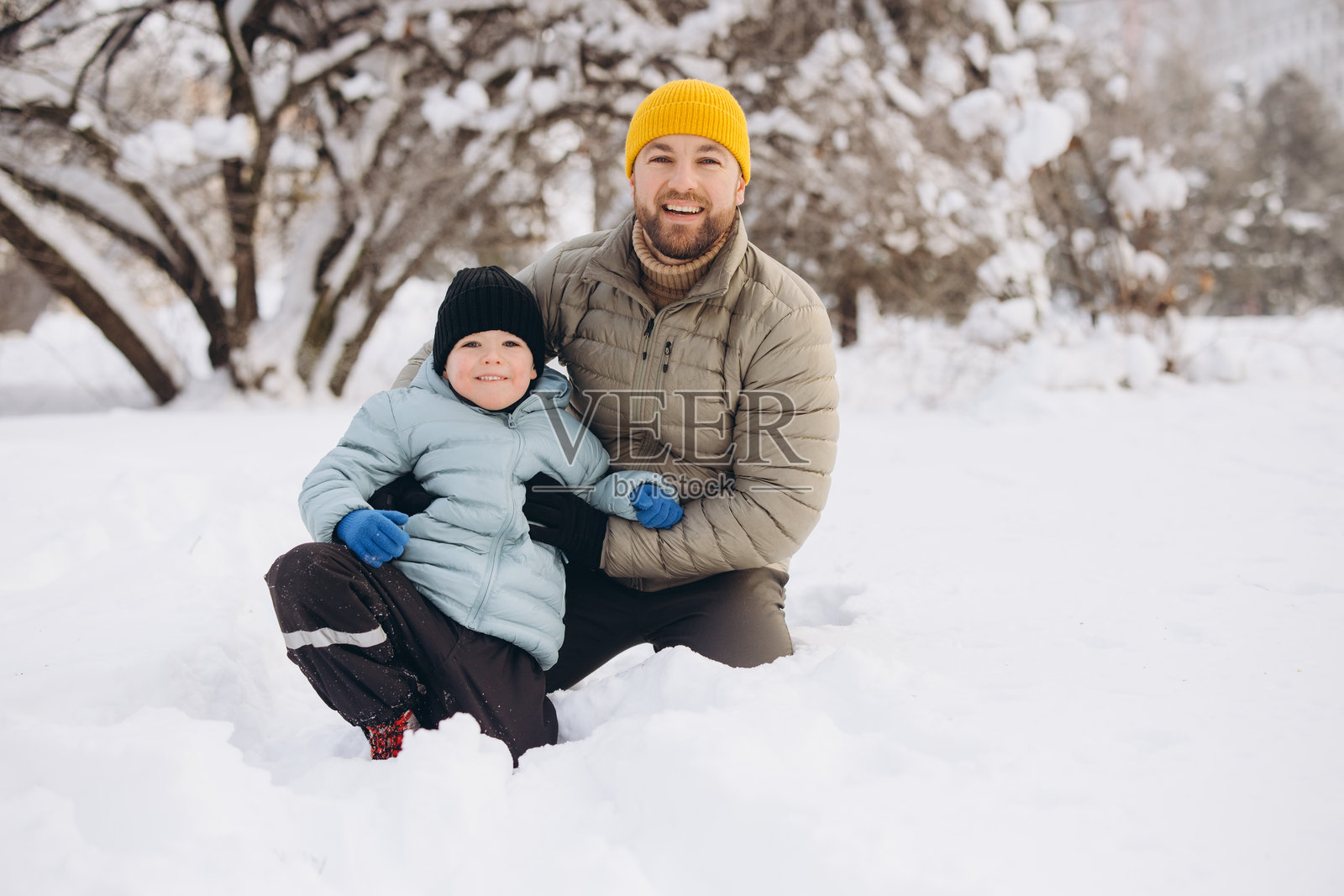 父子俩在雪中亲密互动，享受快乐的户外冬日，展现寒冷季节的家庭生活方式照片摄影图片