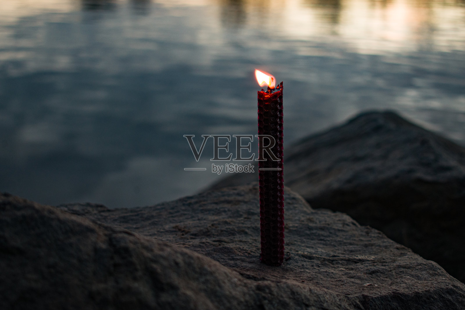 黑暗忧郁氛围中燃烧的红色蜂蜡蜡烛火焰，微距特写照片摄影图片