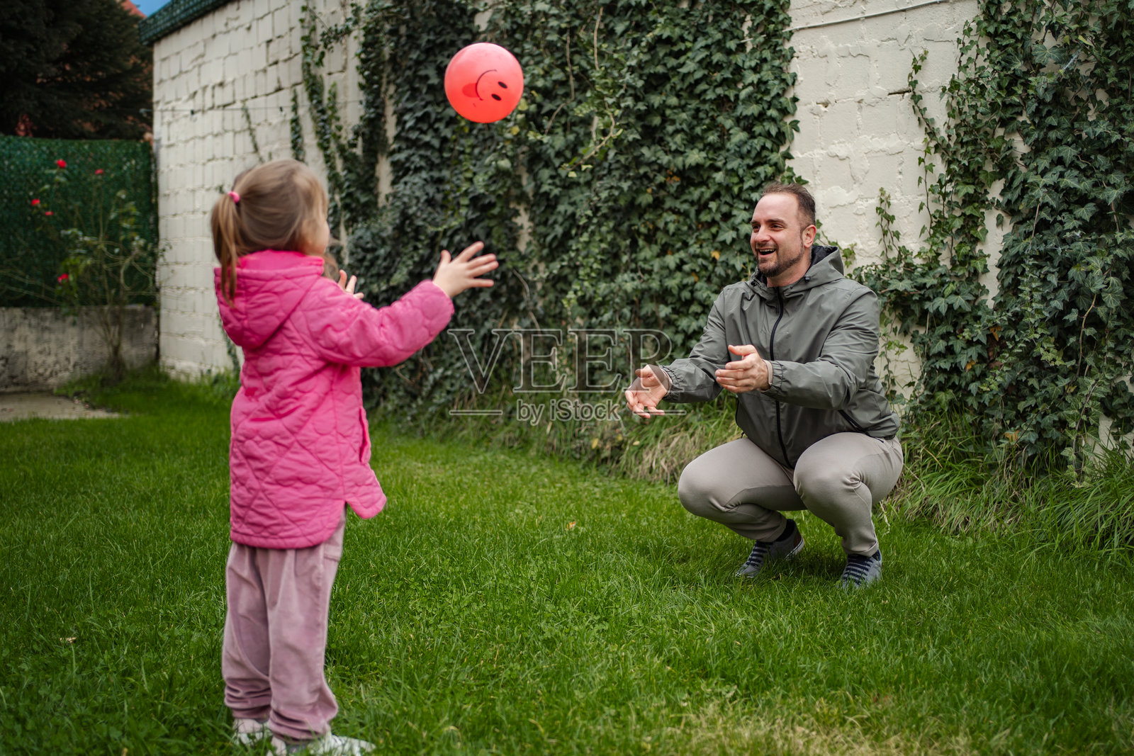 父亲和女儿在后院玩接球游戏照片摄影图片