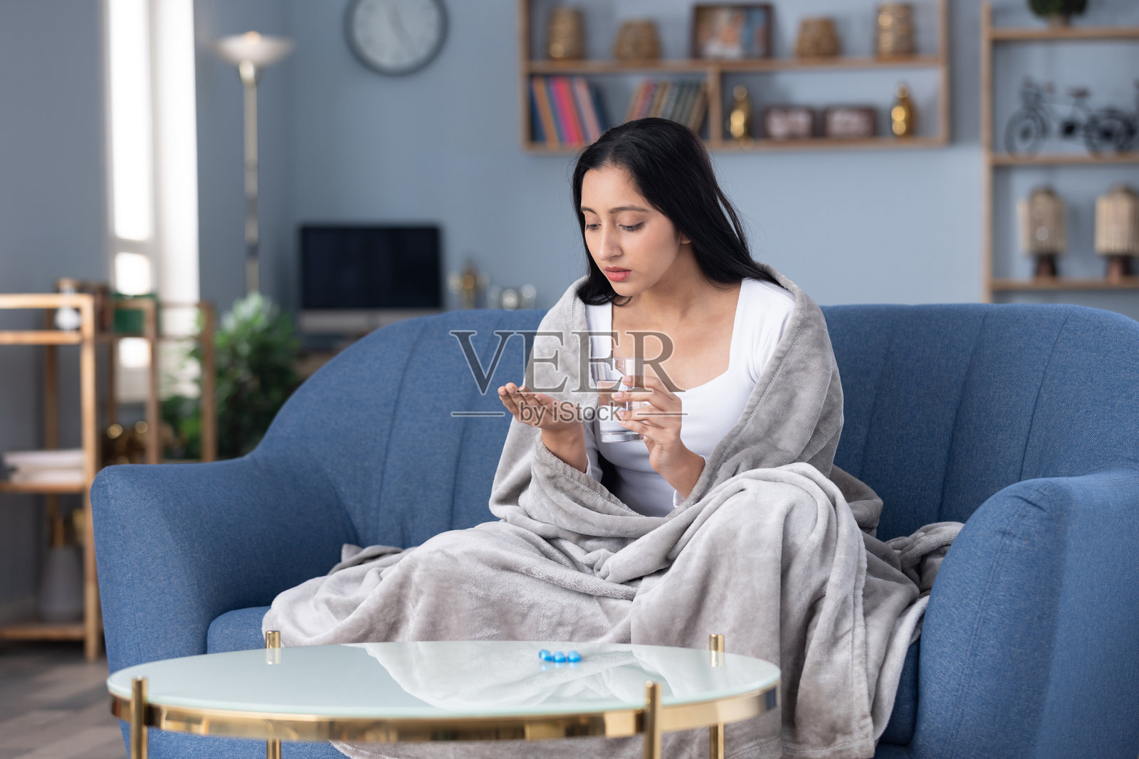 年轻美丽的女子正在服药，旁边放着一杯新鲜的水照片摄影图片