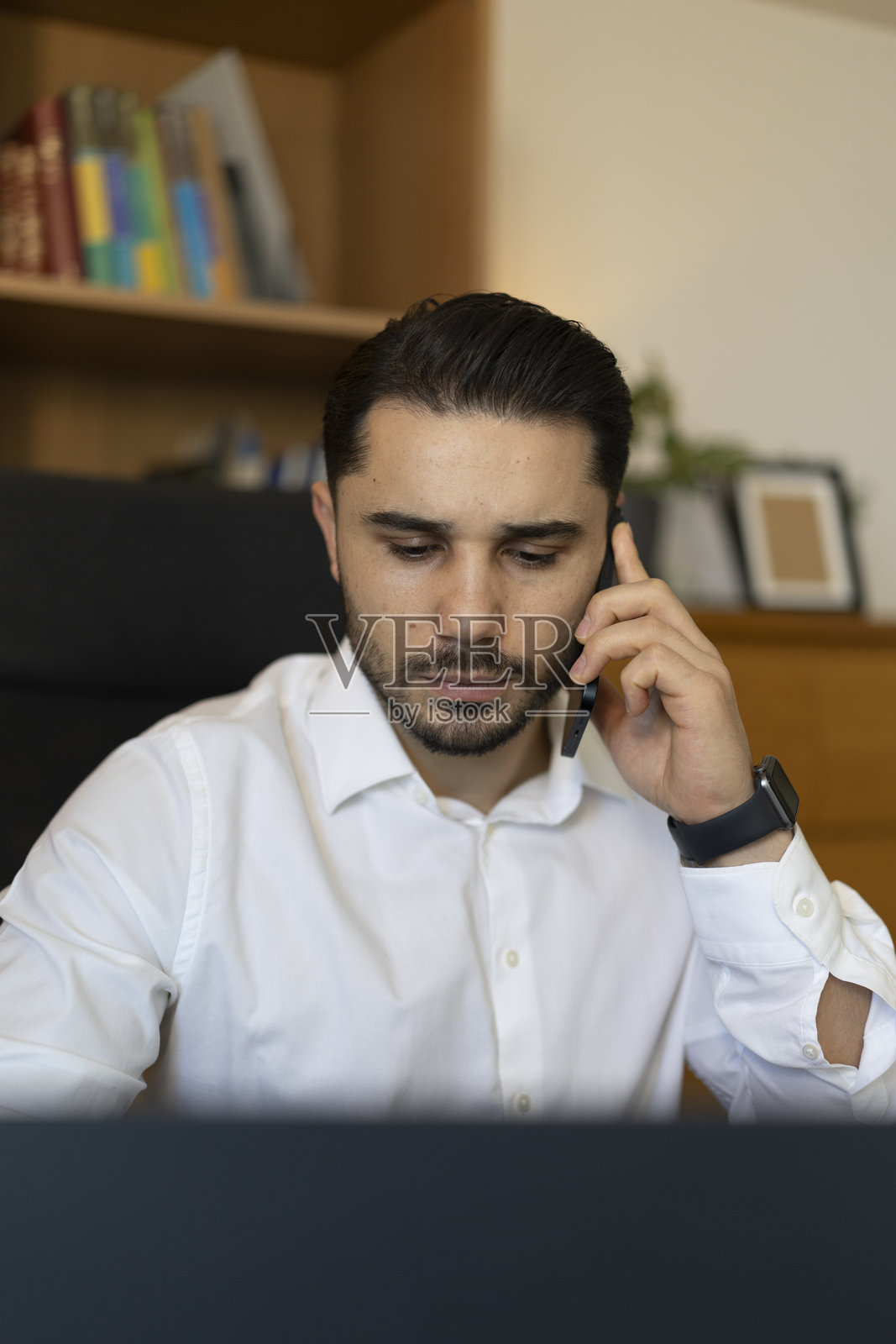 商务人士一边用笔记本电脑工作，一边打电话照片摄影图片