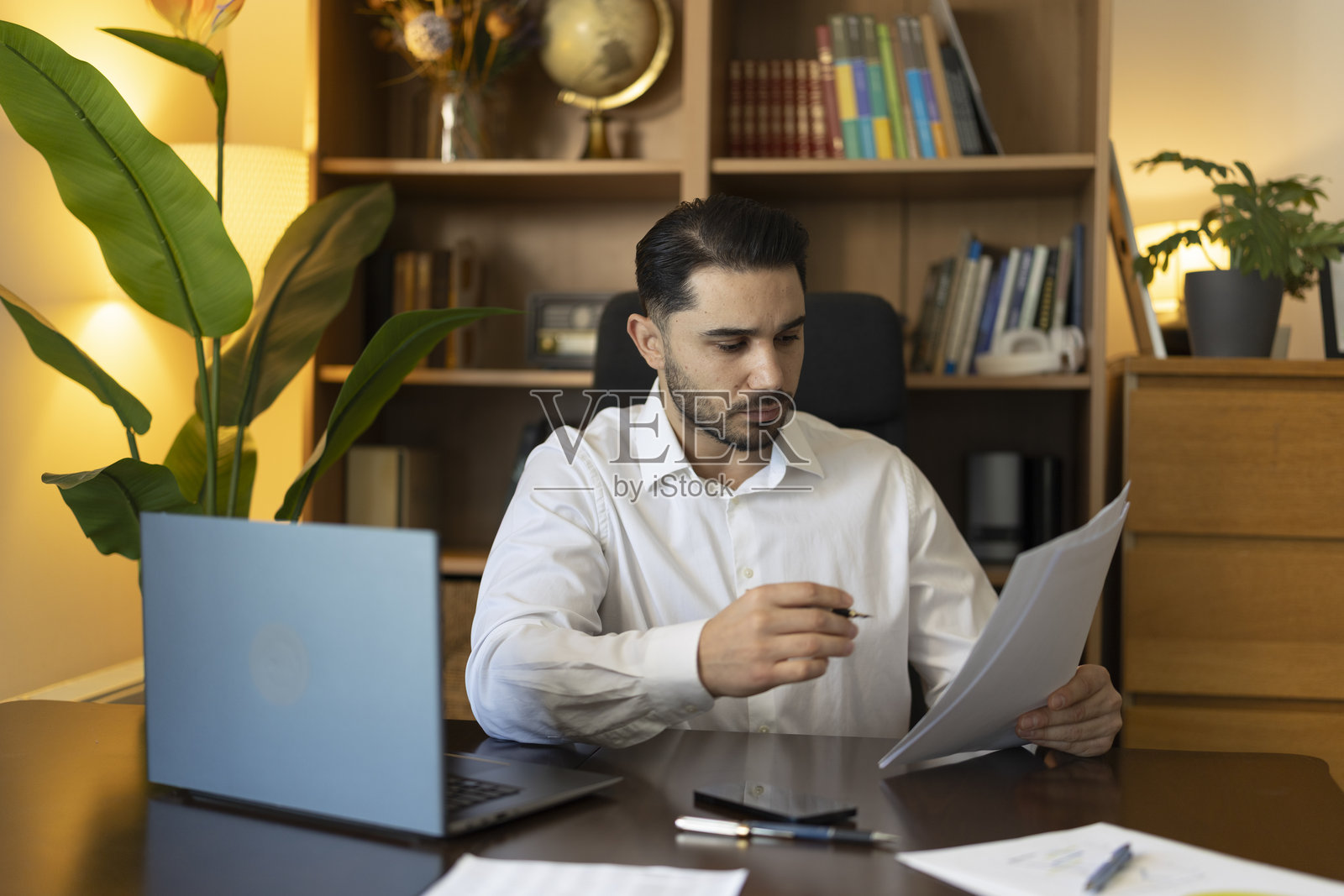 年轻成年男子在家办公，查看文件照片摄影图片