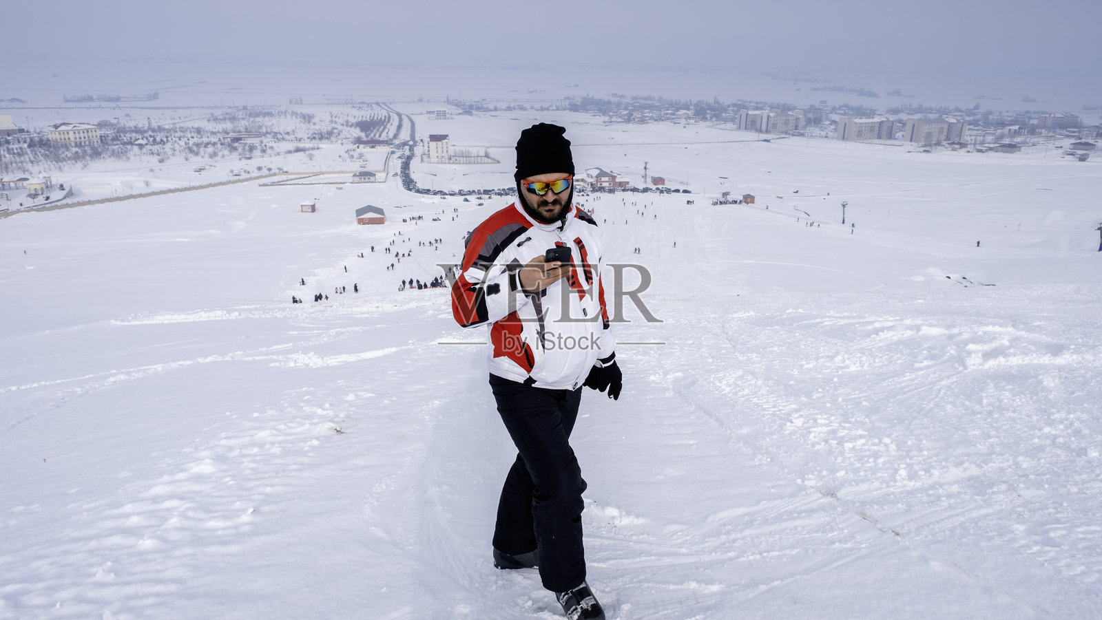 一位滑雪者站在滑雪道上，微笑着环顾四周。滑雪镜、滑雪服特写。照片摄影图片