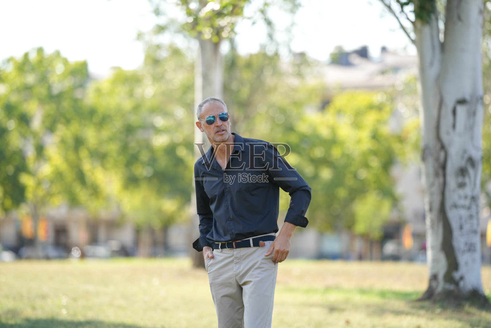 一个穿着黑衬衫和卡其裤的男人正在公园里散步照片摄影图片