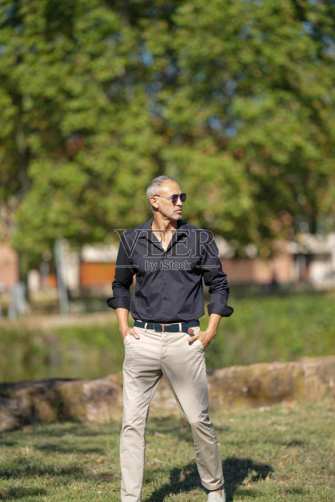 一个穿着黑衬衫和卡其色裤子的男人站在草地上照片摄影图片