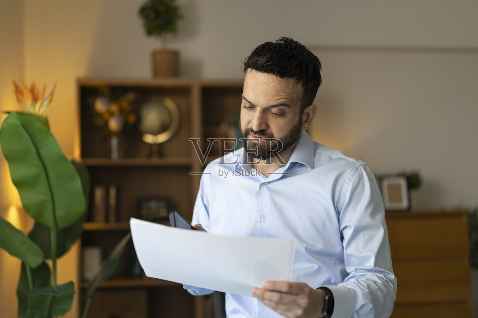 成年男子将文件与智能手机信息进行比对照片摄影图片