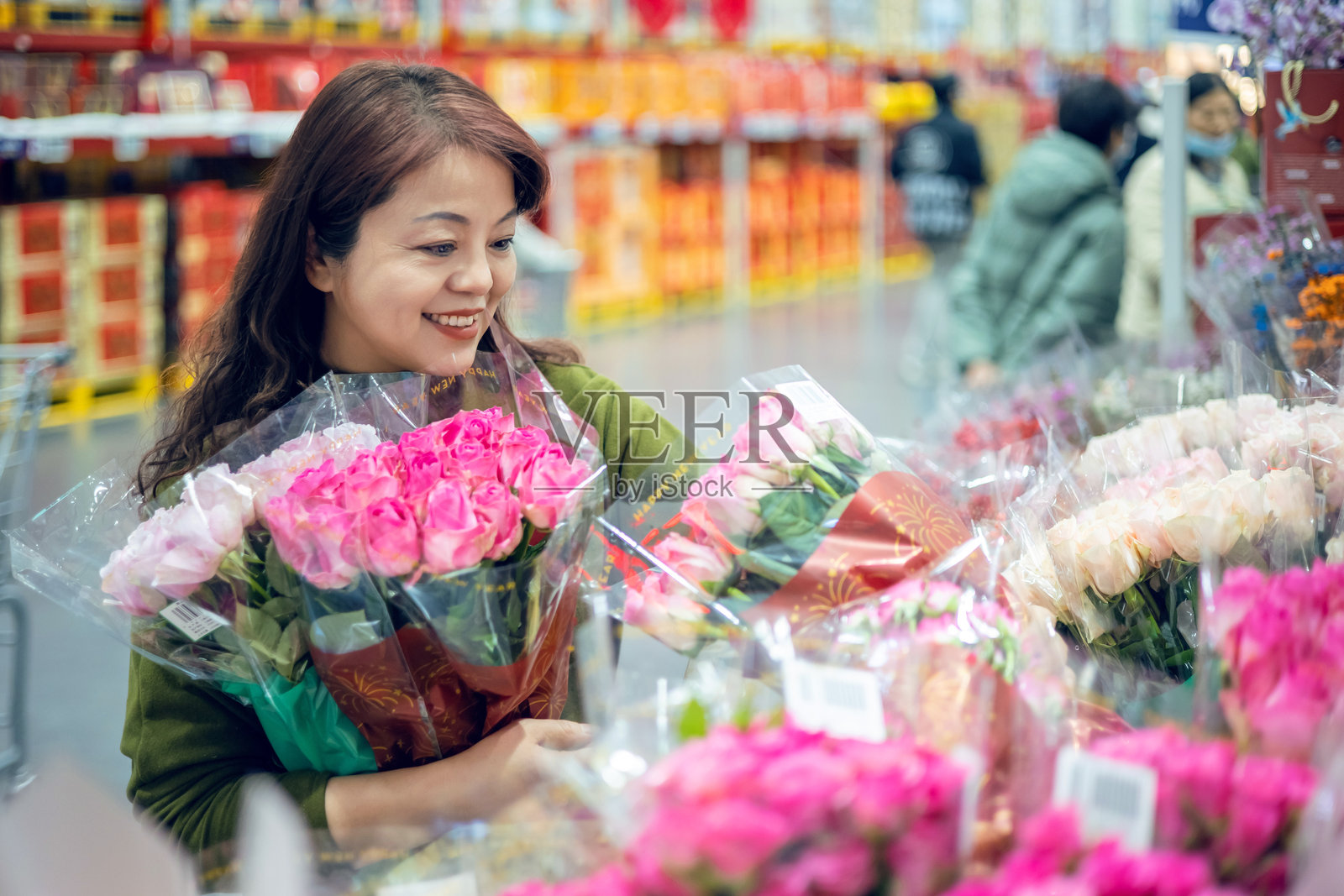 一位中年亚洲女性正在超市里挑选花卉。照片摄影图片