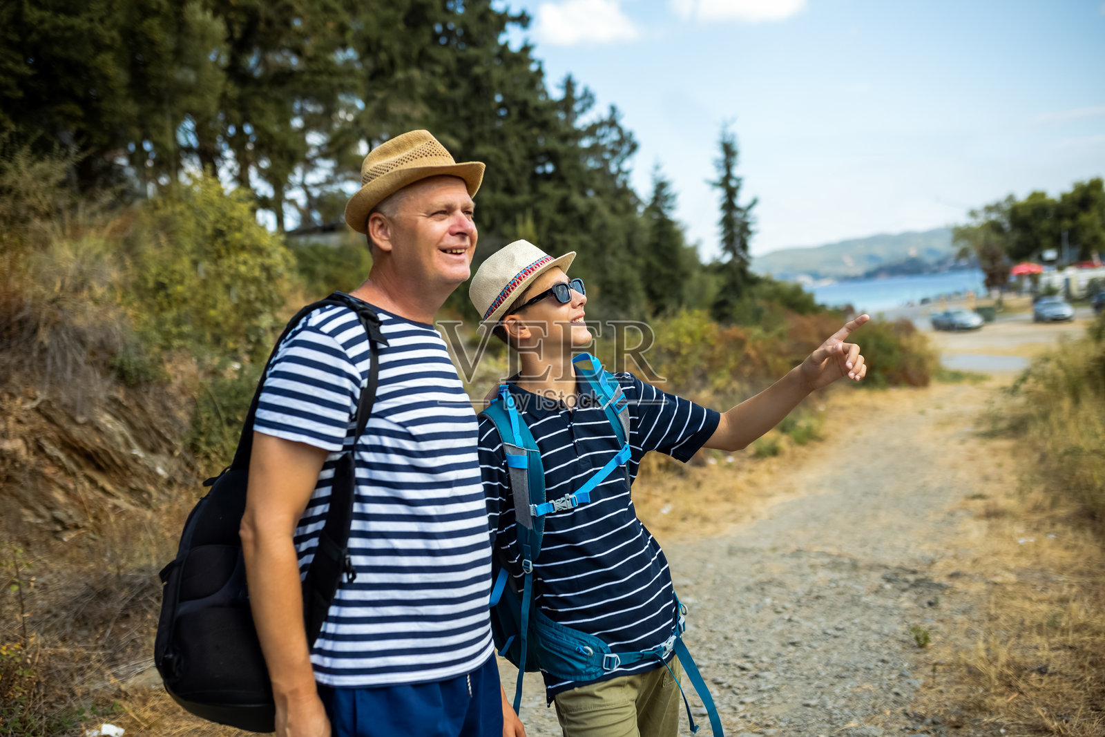 父亲和十几岁的儿子在享受夏日徒步旅行。照片摄影图片