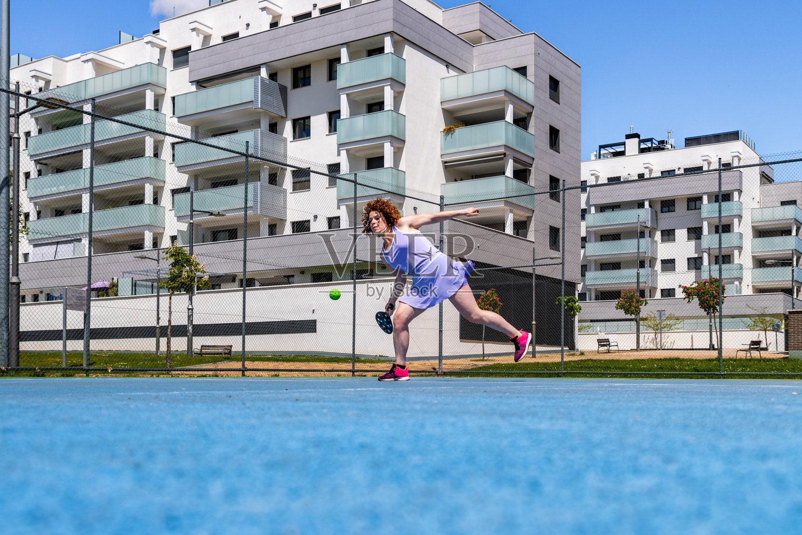 一位女士在充满活力的蓝色球场上打匹克球照片摄影图片