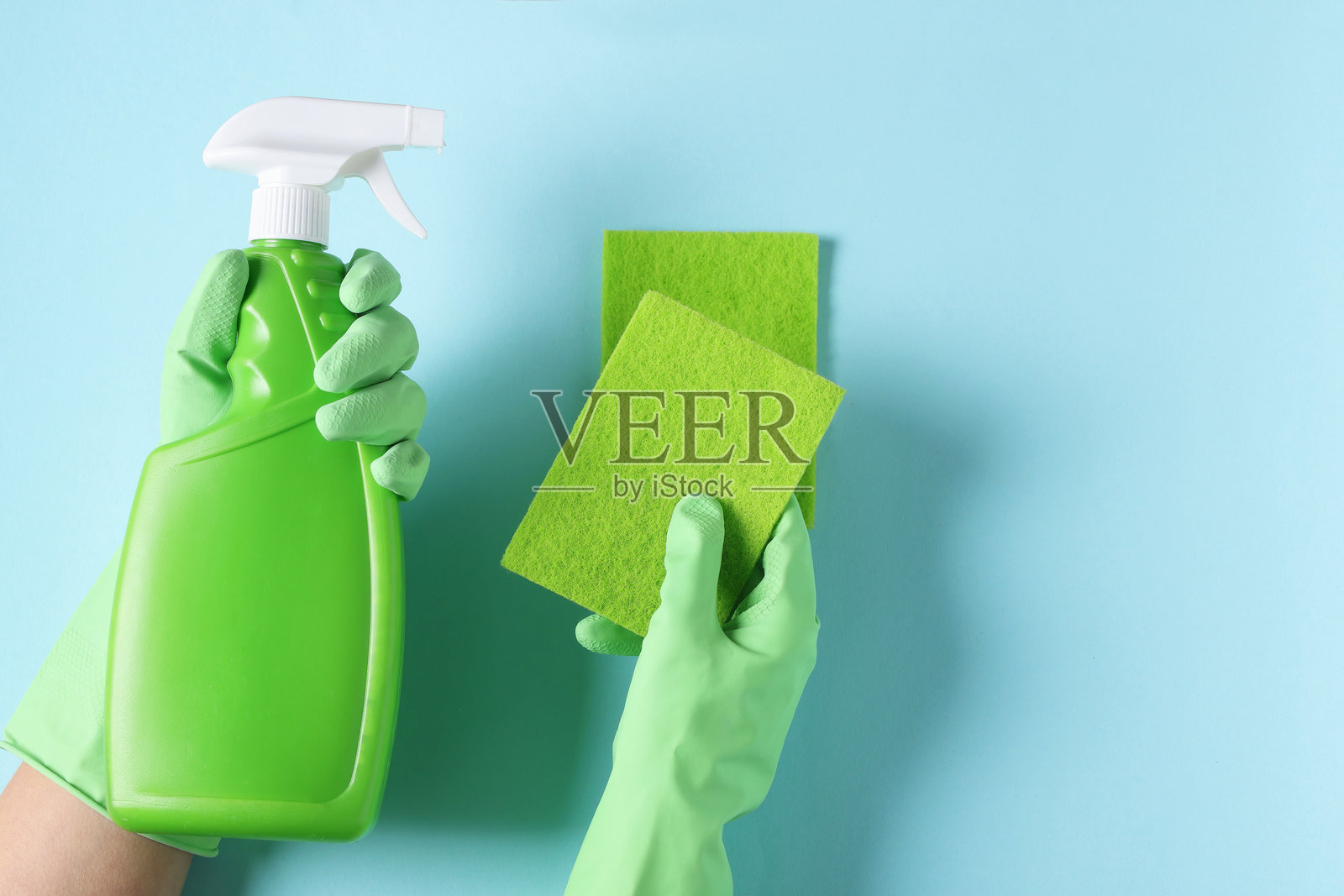 女性，手持清洁产品和海绵，置于浅蓝色背景上，俯视角度，留有文字空间。照片摄影图片