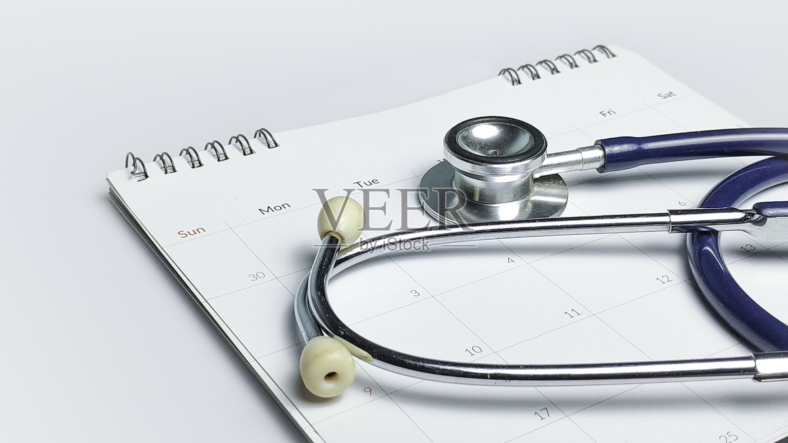 医疗预约概念，白色背景上的听诊器和螺旋日历，用于医疗保健日程安排照片摄影图片