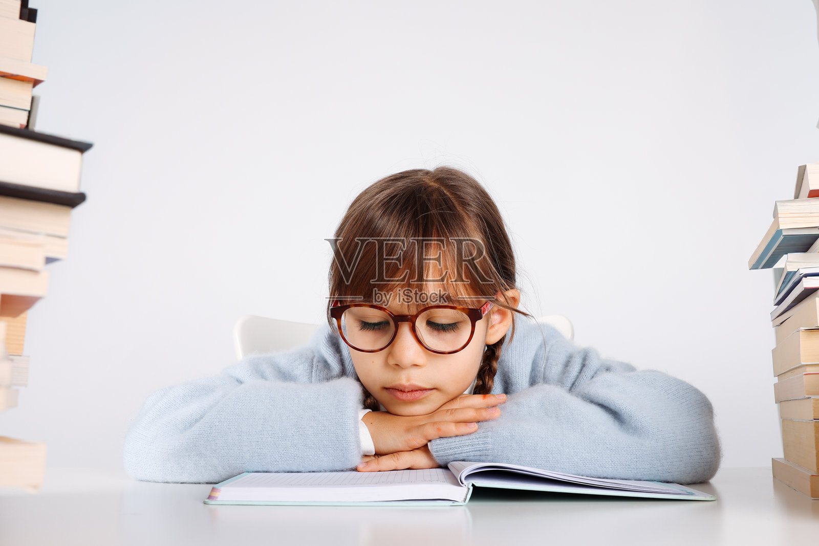 疲惫又厌倦的小女孩，身边堆满了书照片摄影图片