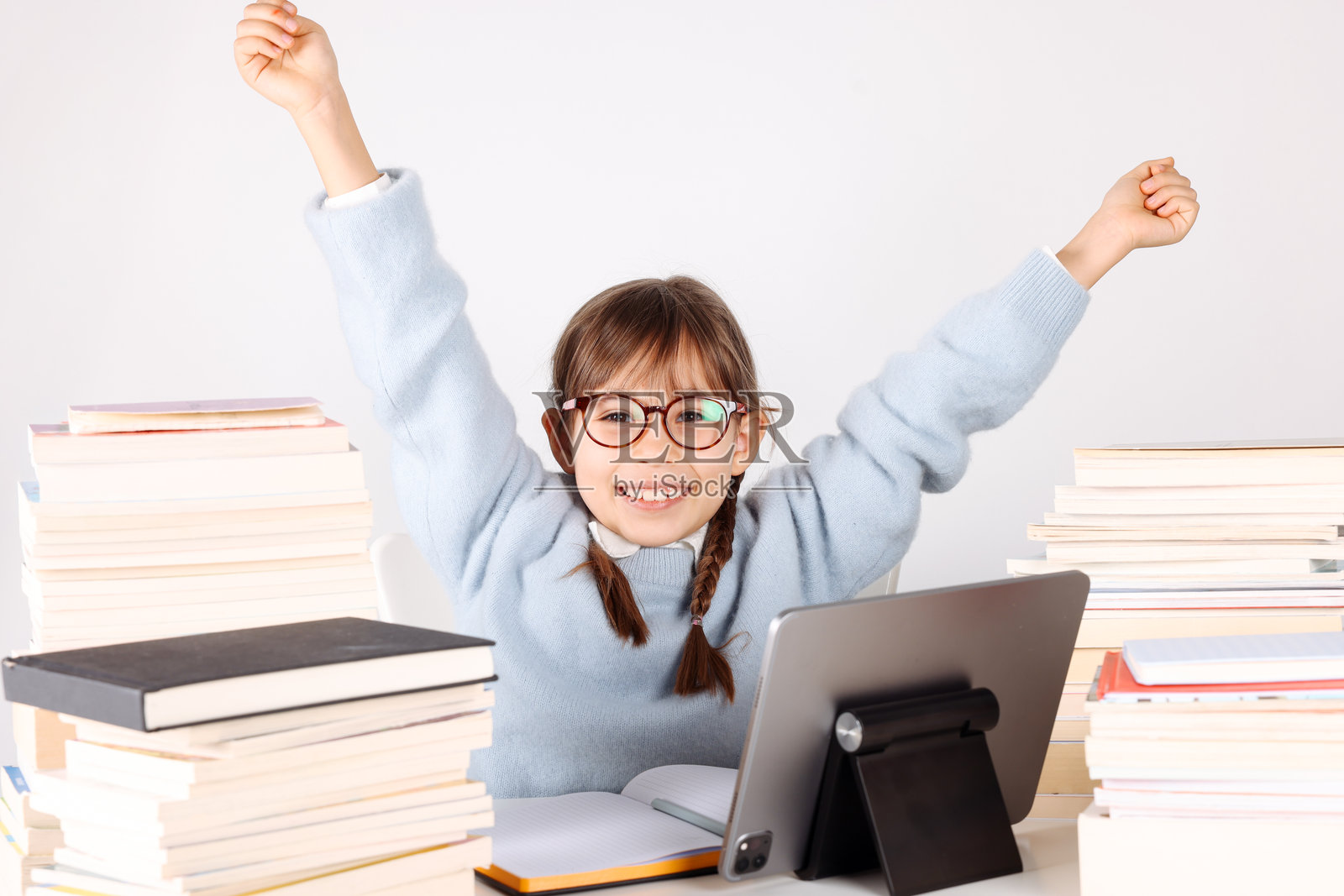 小女孩在书堆中用平板电脑做功课照片摄影图片