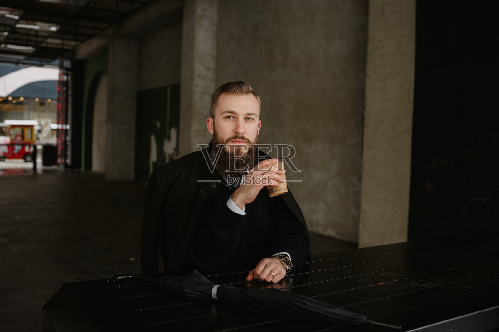 自信的商人在城市空间的一张桌子旁喝咖啡照片摄影图片