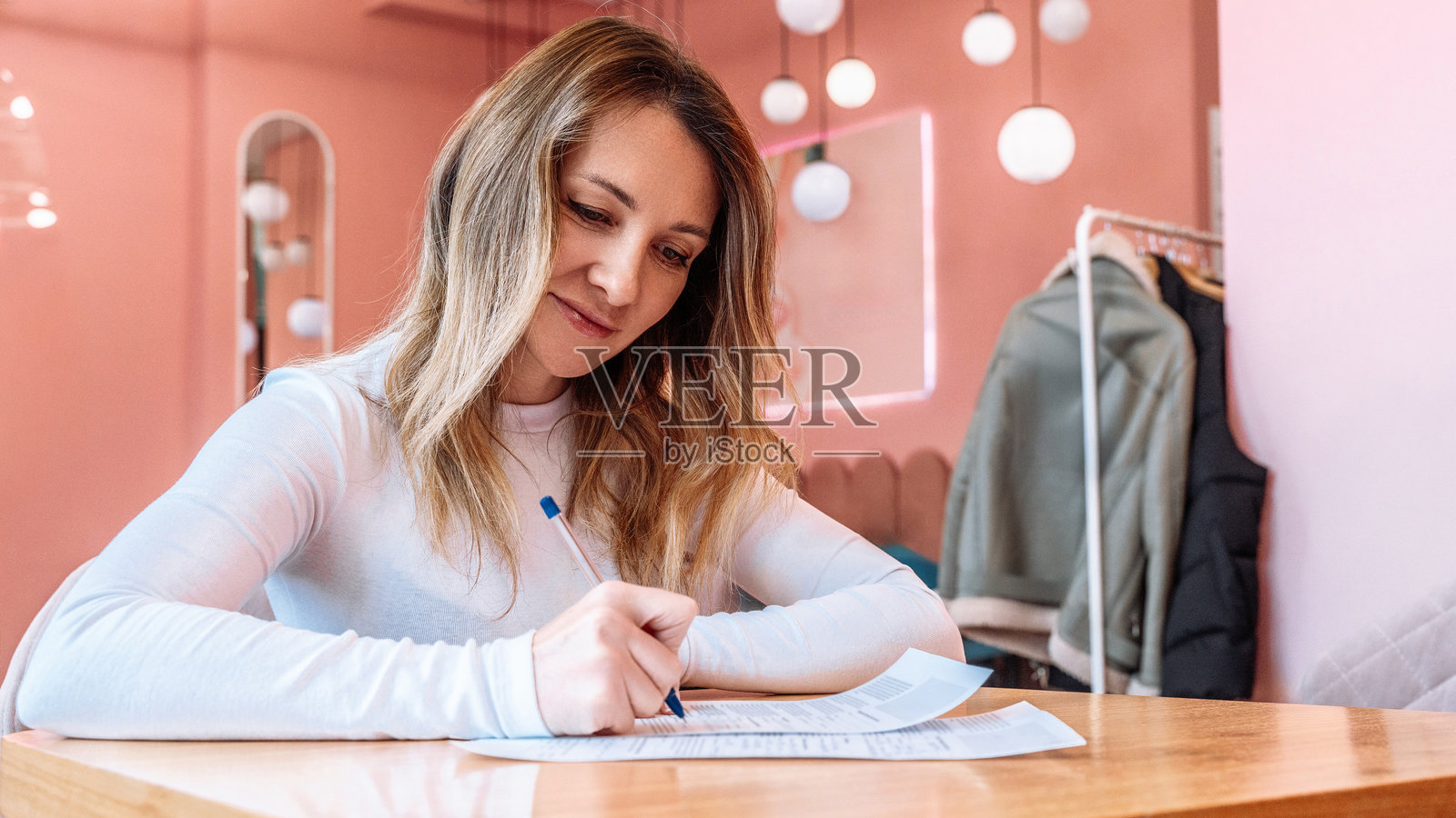 明亮的房间里，一位女士正在纸上书写，准备报税照片摄影图片