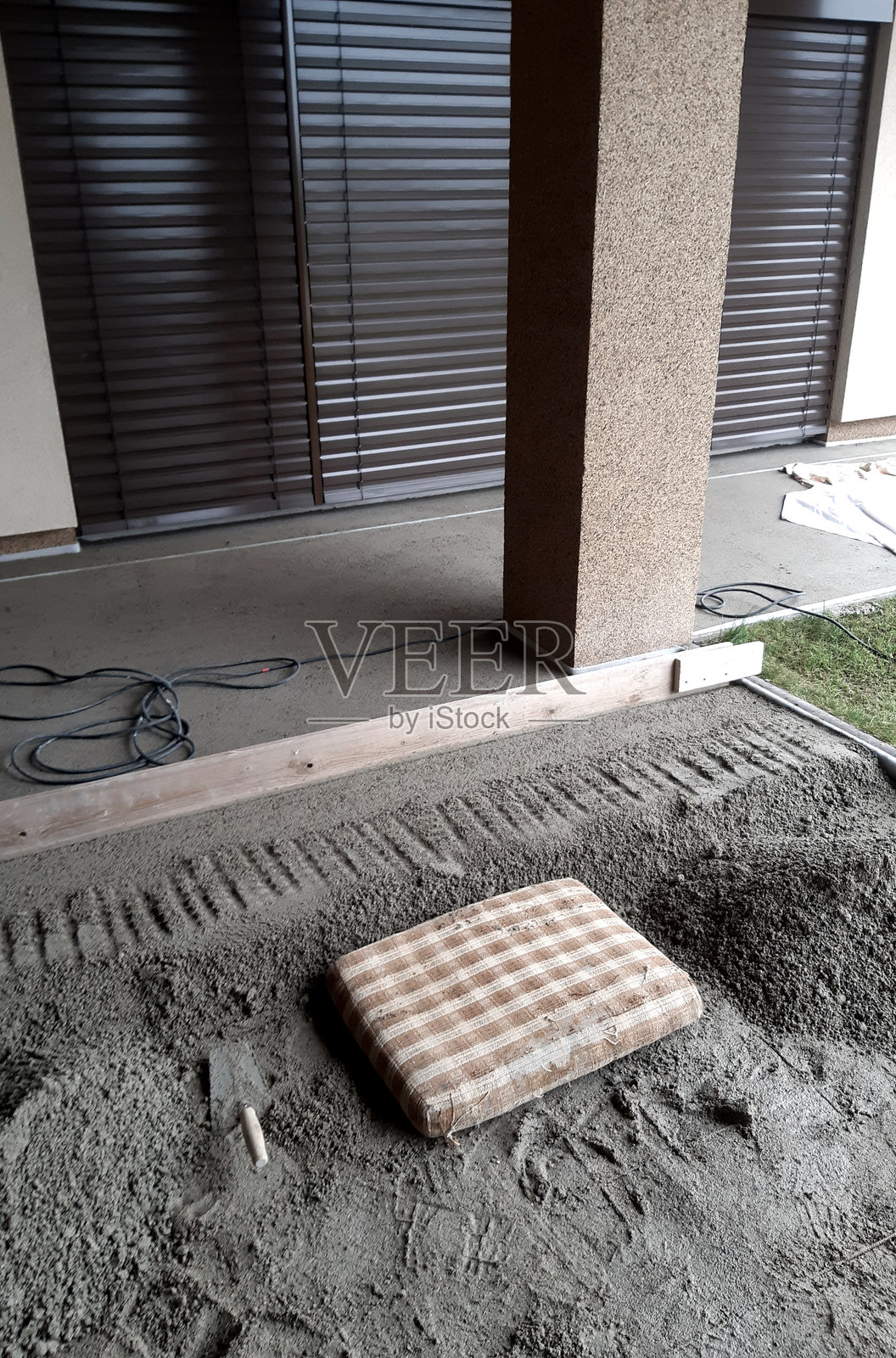 正在浇筑混凝土用于庭院或人行道。根据图片显示，已铺设了防潮层塑料薄膜和钢筋网，并且正在铺展湿混凝土。照片摄影图片