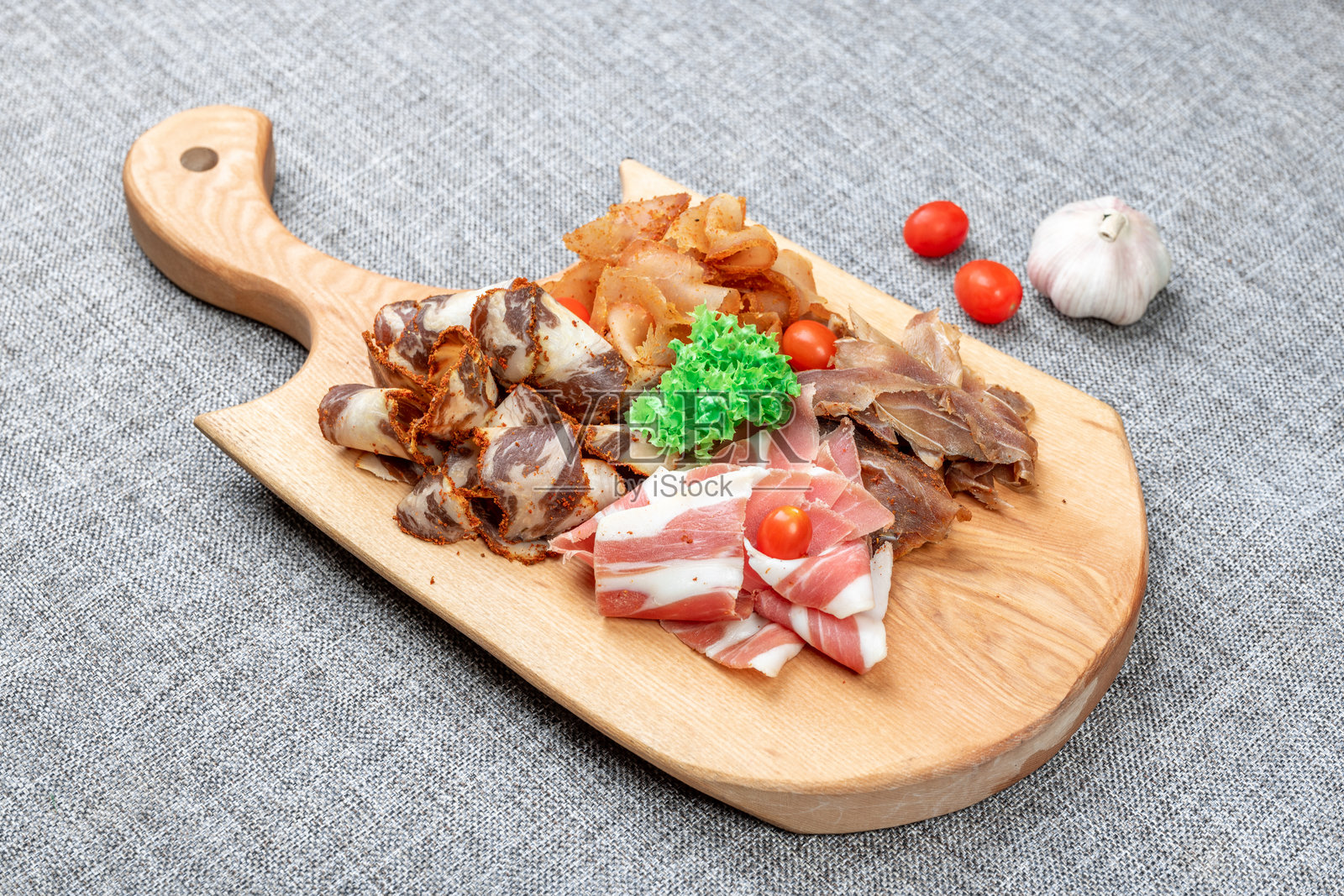 乡村木板上盛有各种熏制和腌制肉类拼盘，包括巴斯图尔马香肠、培根和风干肉，作为冷盘开胃菜照片摄影图片