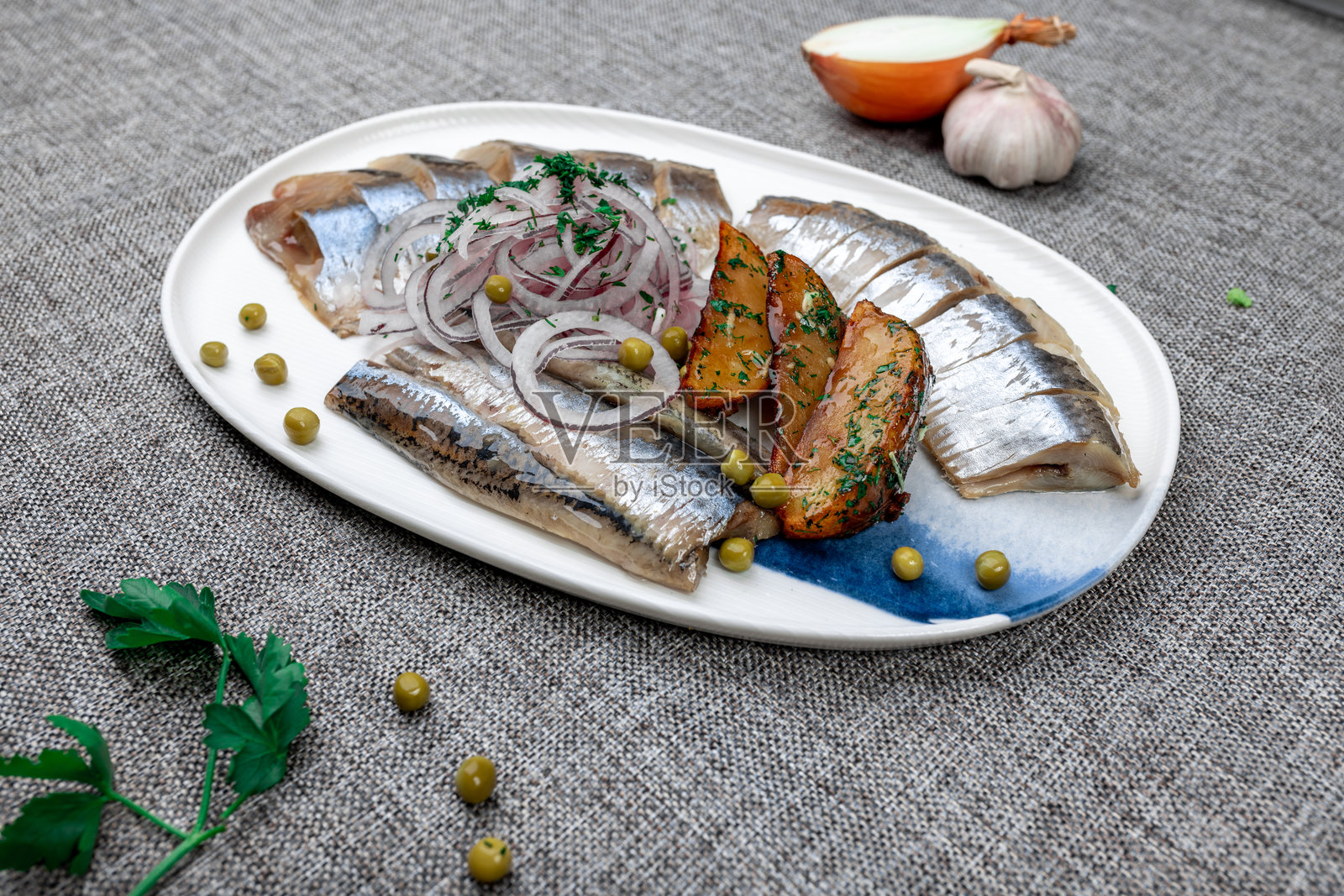 传统的俄罗斯冷盘（扎库斯基），包含腌鲱鱼、烤土豆和红洋葱照片摄影图片