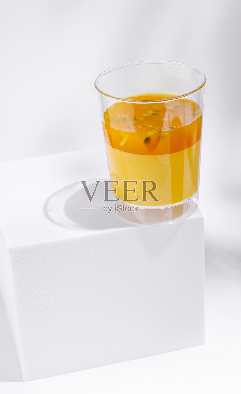 白色底座上的透明杯中清爽的橙色饮料照片摄影图片