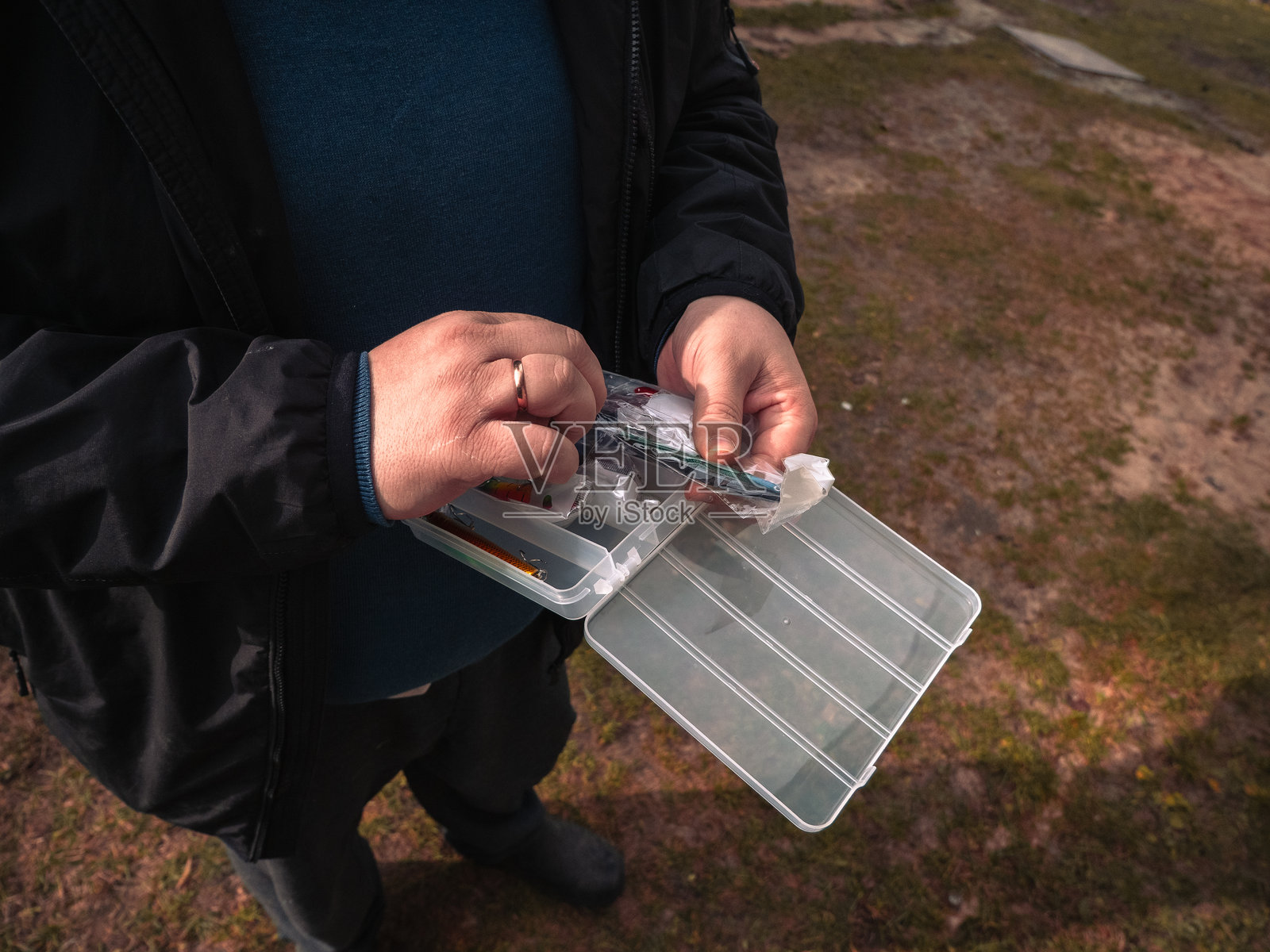 对鱼钩和鱼圈进行彻底检查。一个人正在检查色彩鲜艳的渔具质量。一个人正在评估色彩鲜艳的鱼钩的质量和状况。照片摄影图片