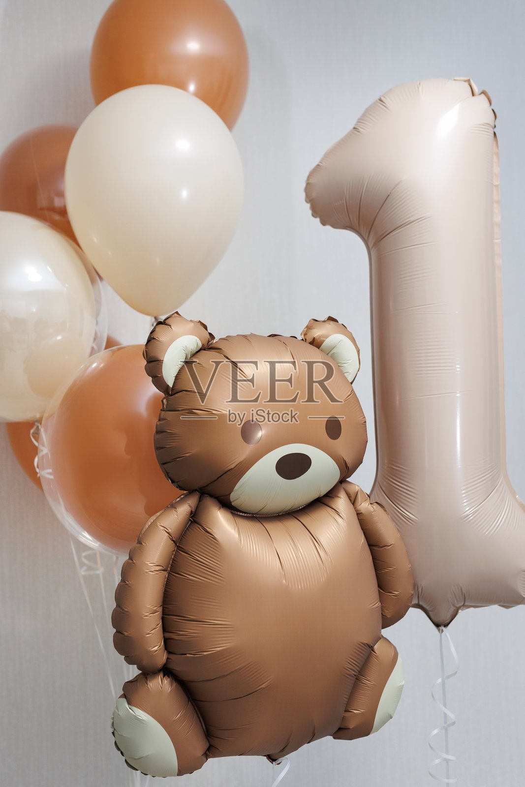 特写镜头下，米色和棕色氦气球、数字1箔气球和一个泰迪熊。照片摄影图片