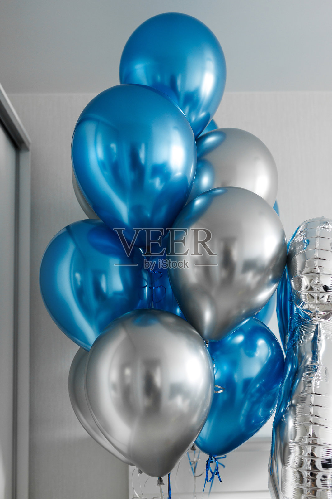 生日派对上公寓室内成束的蓝色和银色氦气球。照片摄影图片