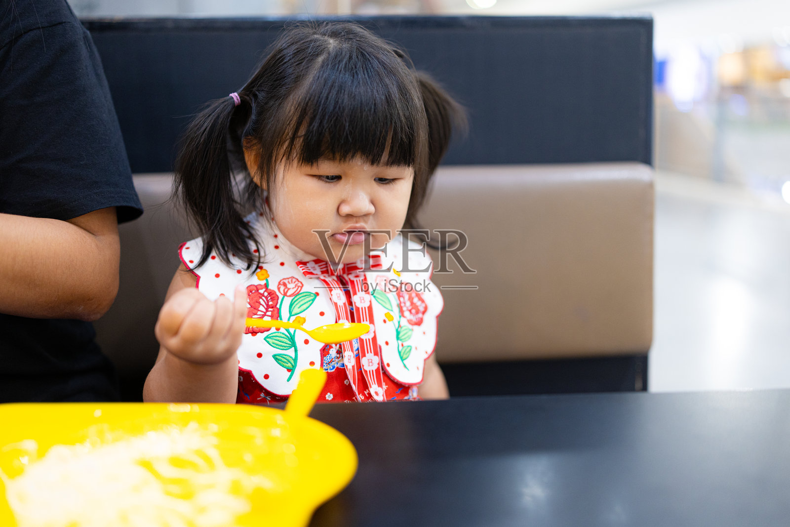 可爱的小女孩在餐厅吃饭时做出不高兴的表情。照片摄影图片