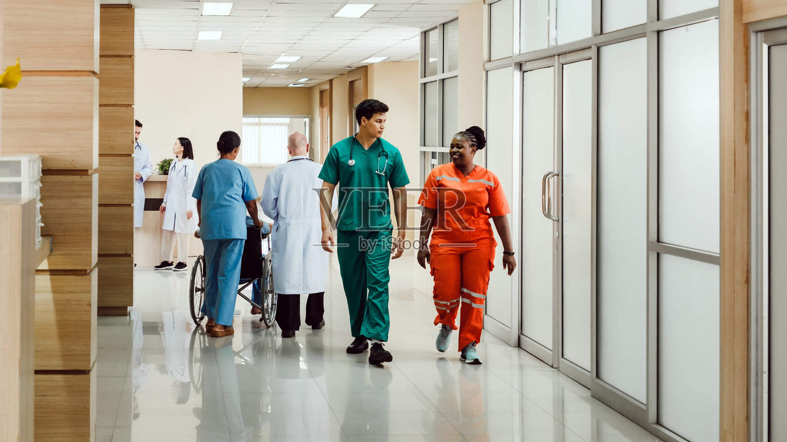 身穿手术服的医护人员在明亮的医院走廊里讨论，体现了团队合作、信任和关怀。一个专注于协作和患者福祉的现代医疗环境。照片摄影图片