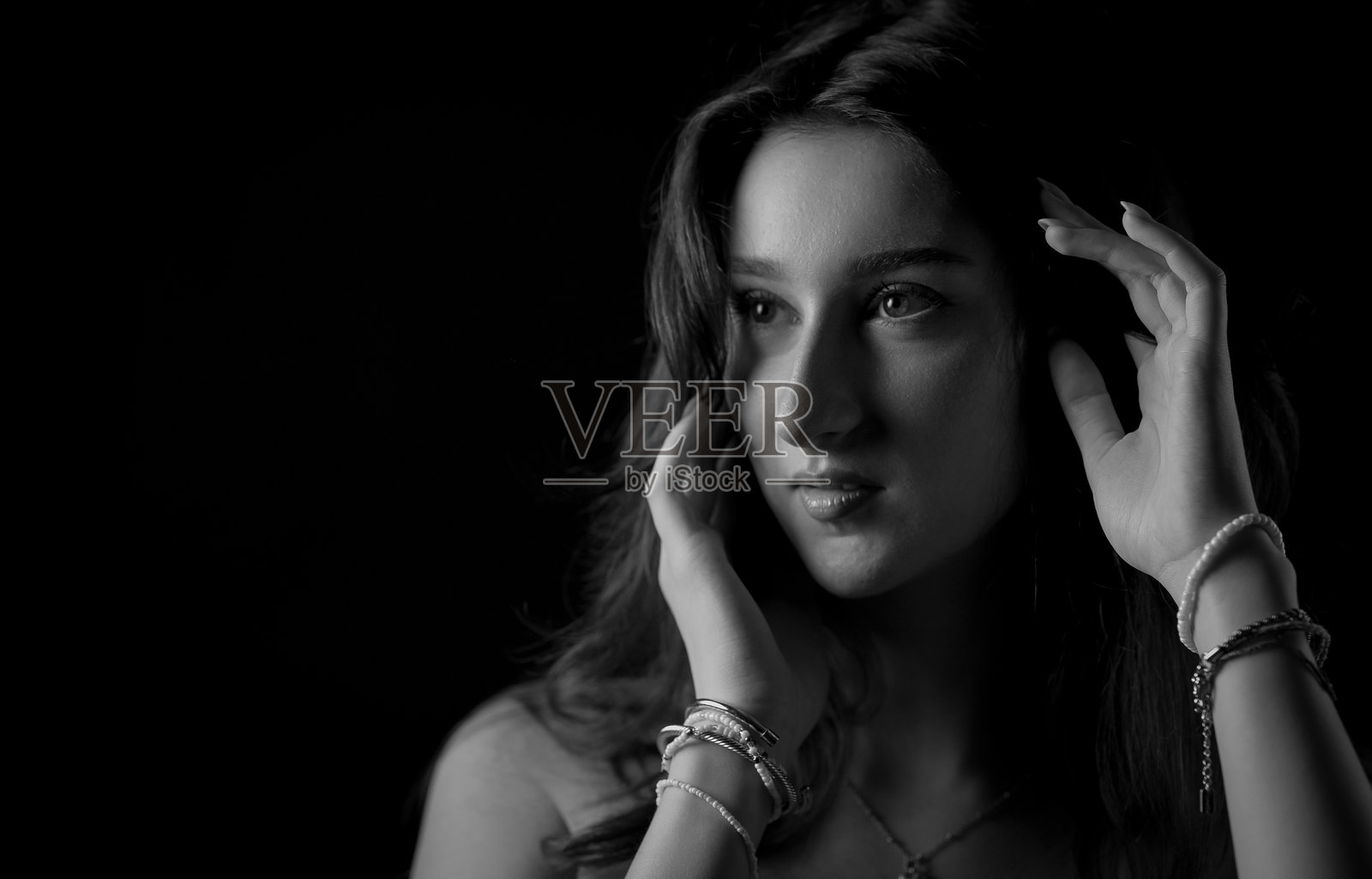 黑白肖像：年轻女子抚摸头发，目光移开照片摄影图片