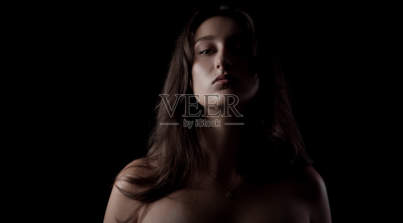 年轻女子长棕发在影棚黑背景前摆拍肖像照片摄影图片