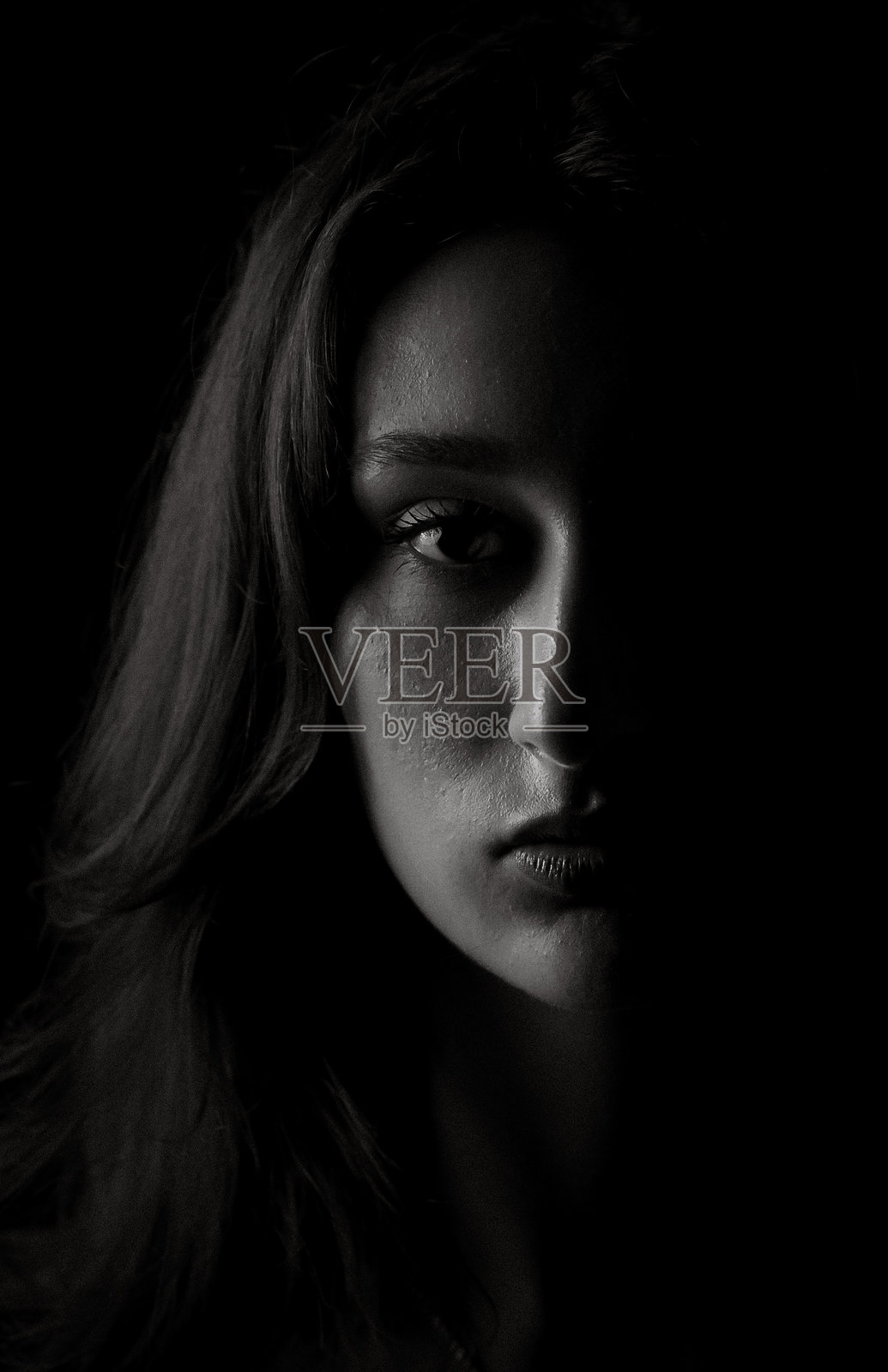 年轻女子从黑暗中露出半张脸照片摄影图片