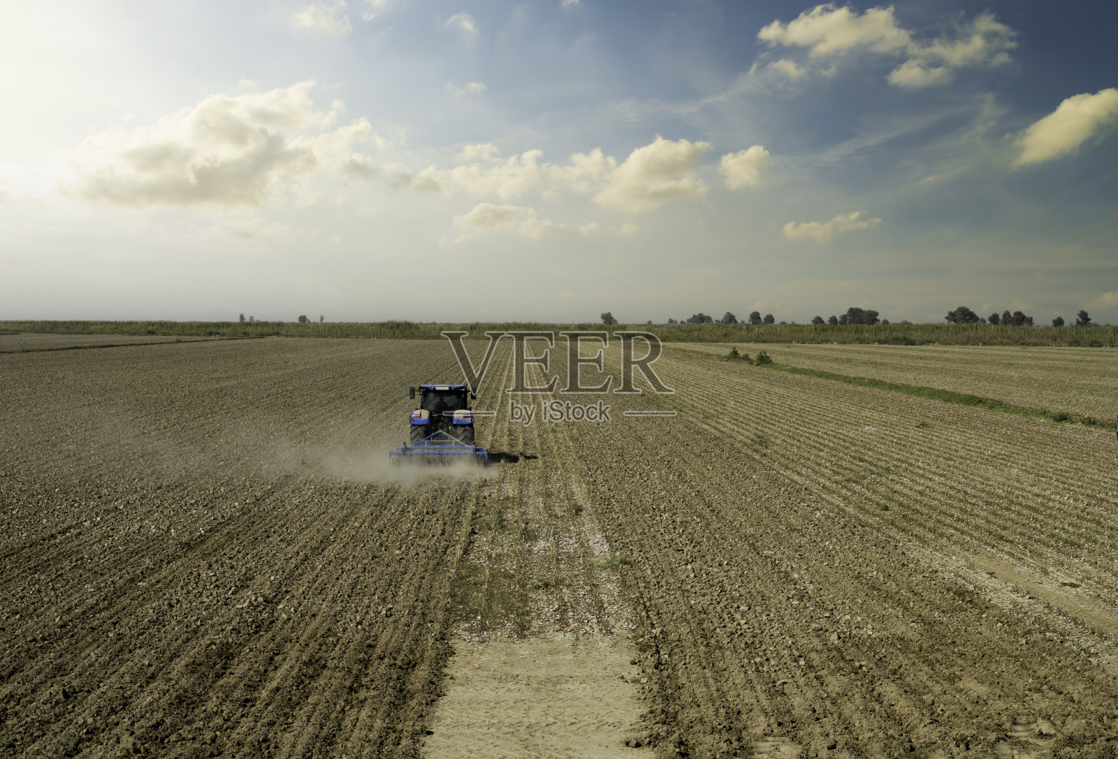 一辆大型拖拉机正在耕地。照片摄影图片