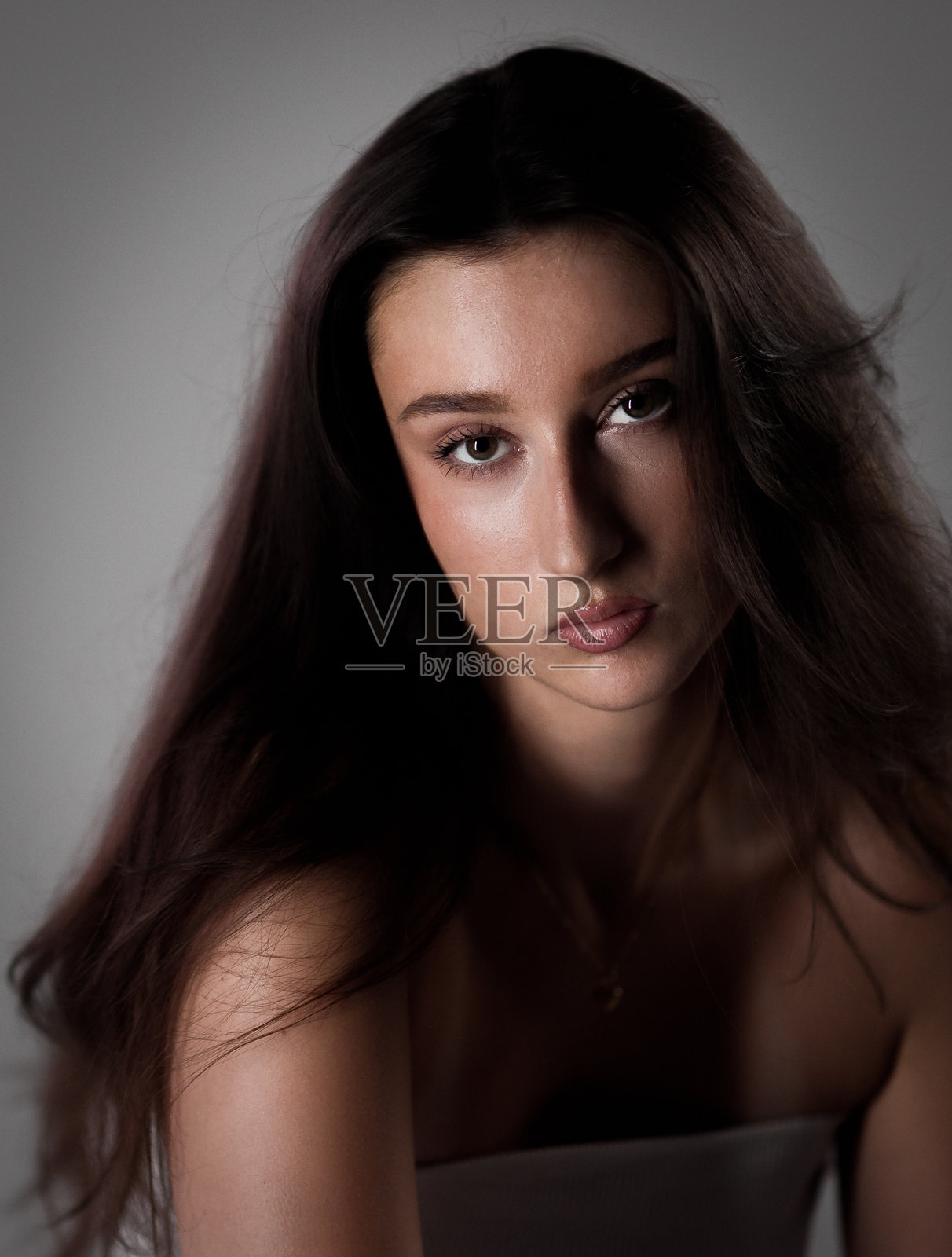 一位留着长棕发的严肃年轻女子在影棚摆姿势的肖像照照片摄影图片