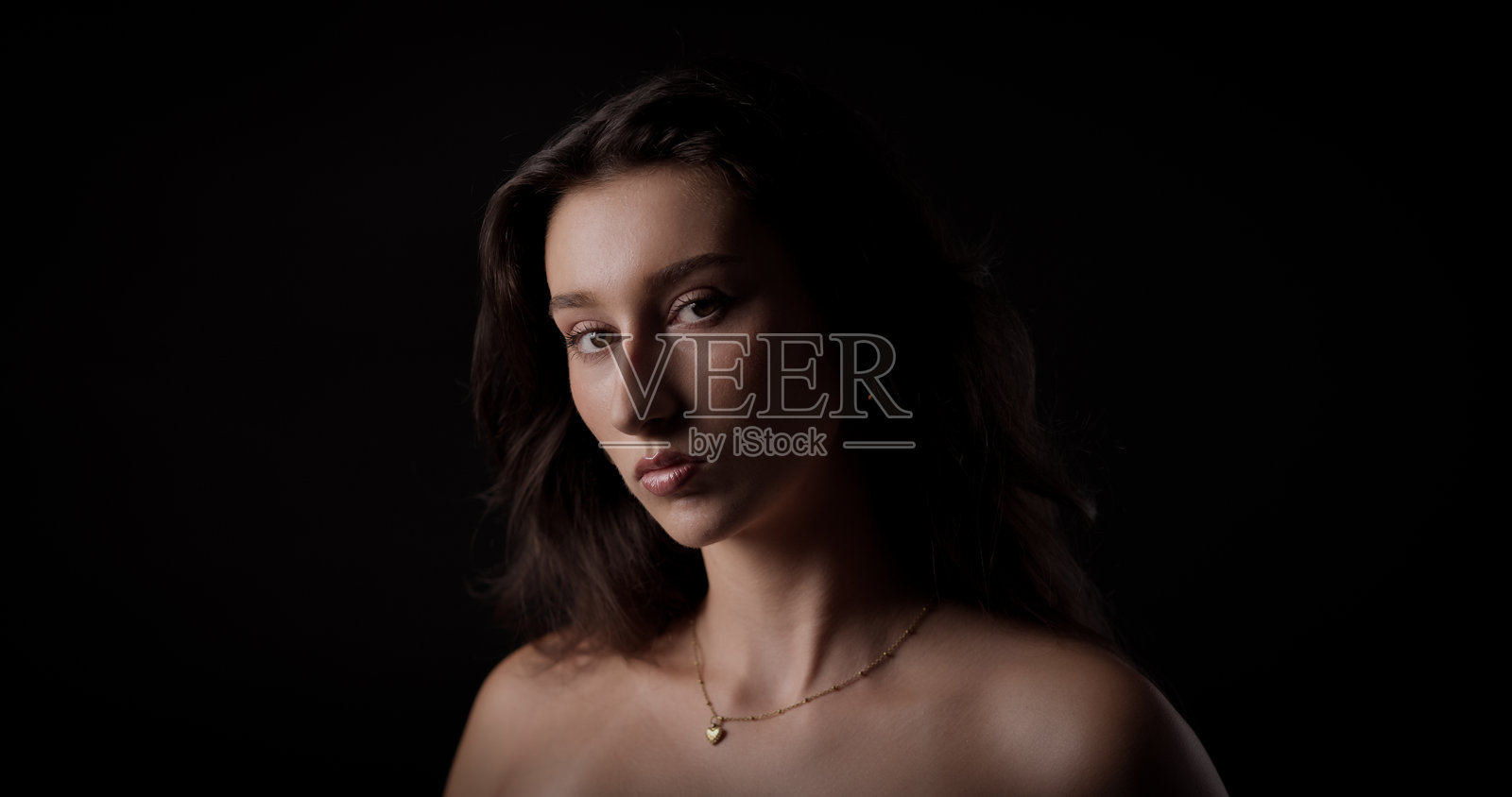 年轻女子在黑暗背景下摆出严肃的表情照片摄影图片