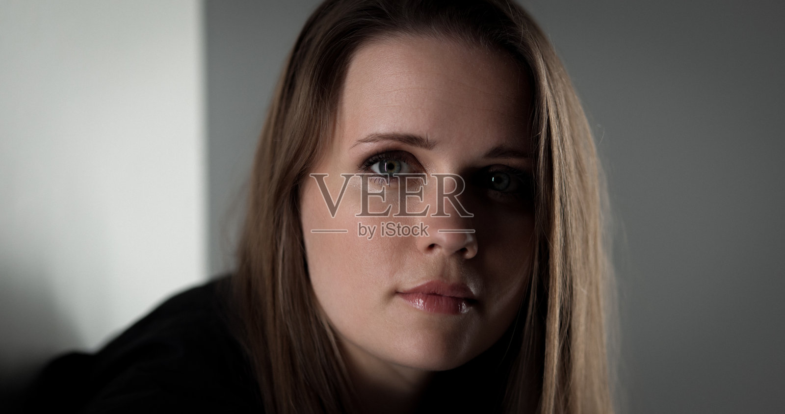 一位留着长棕色头发的年轻女子在影棚里摆出严肃的表情照片摄影图片