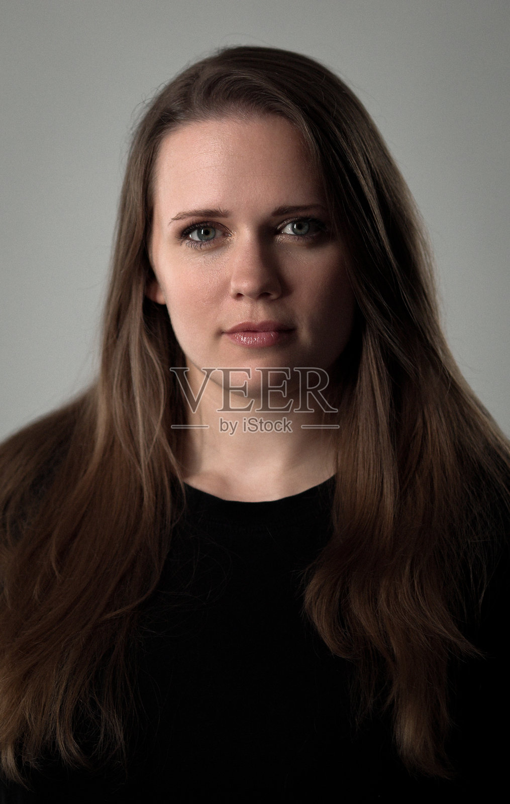 身穿黑衬衫、留着棕色长发的年轻女子肖像照片摄影图片