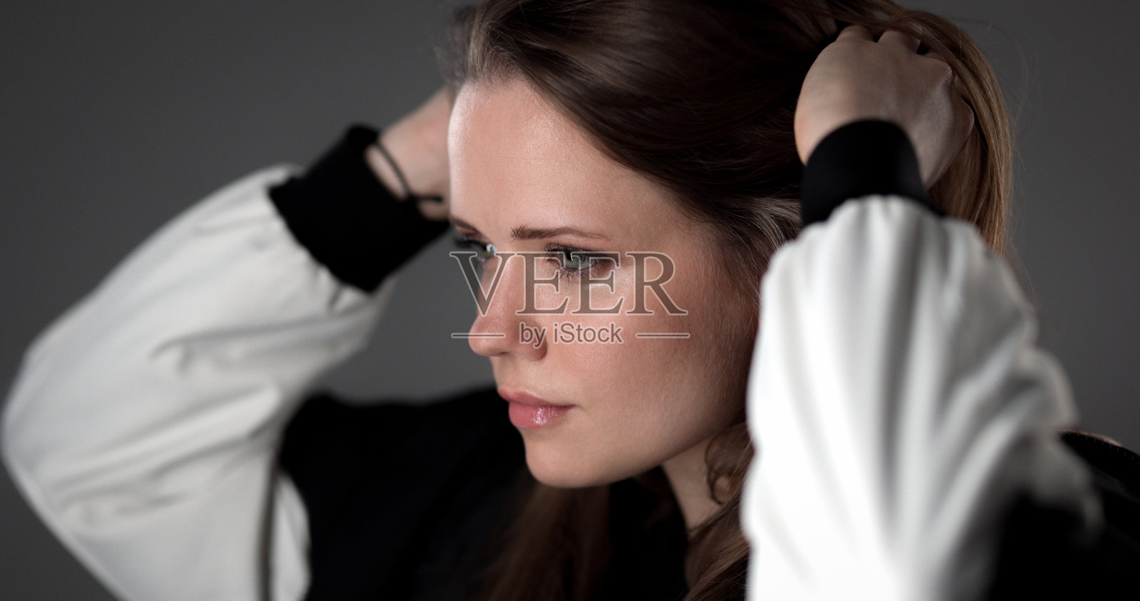 年轻女子在灰色背景上手捋头发照片摄影图片