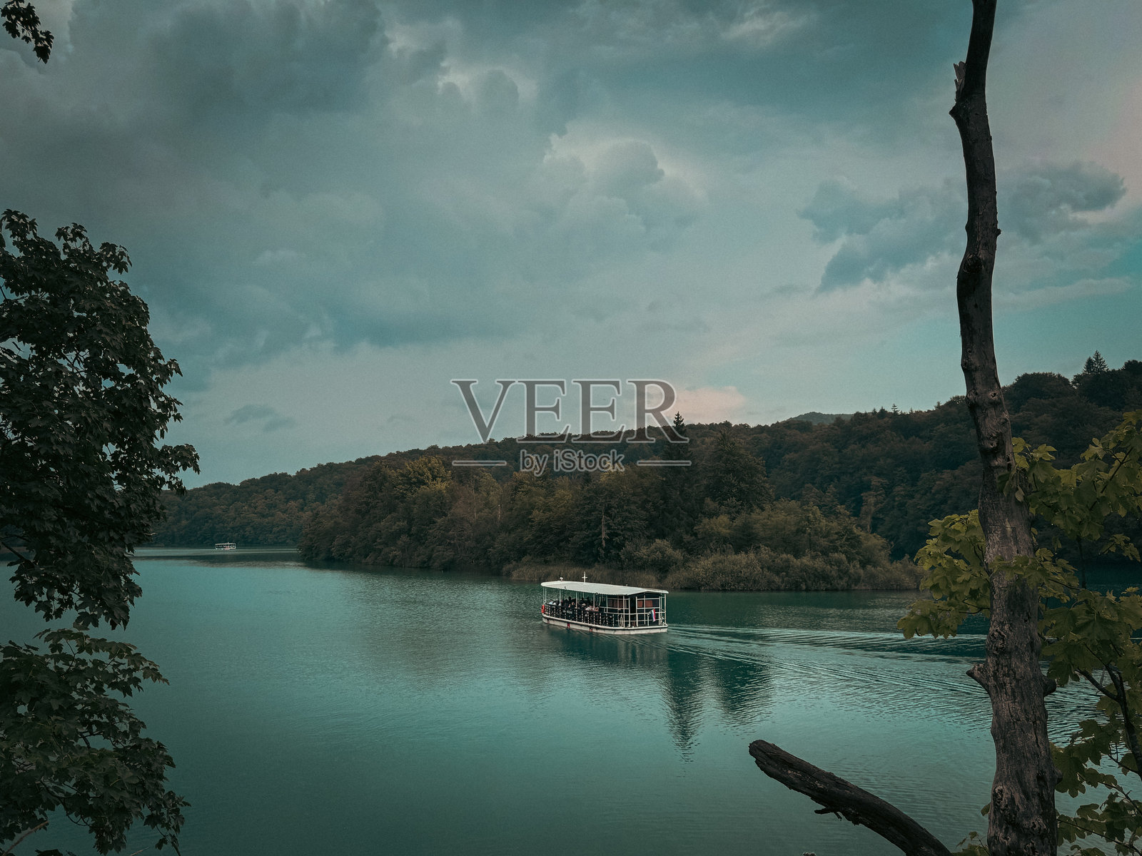 宁静湖泊上的一叶扁舟，四周环绕着森林照片摄影图片