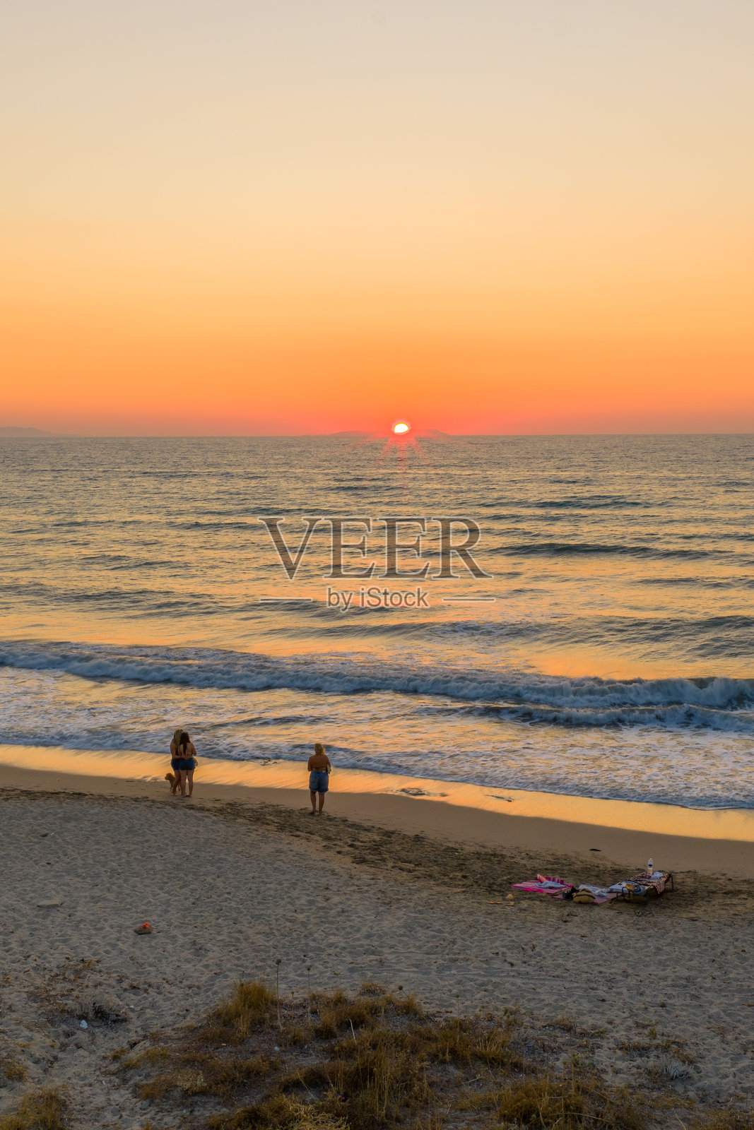 宁静的日落映照着金色沙滩，温柔的海浪拍打着岸边，是海边浪漫宁静夜晚的完美写照，捕捉了自然之美和度假氛围。照片摄影图片