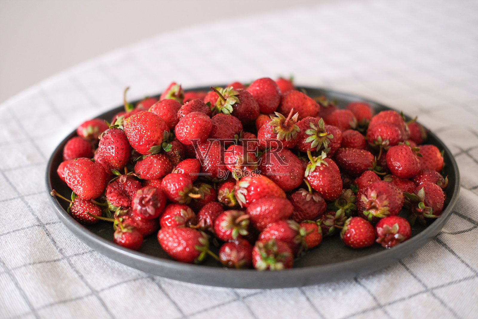 桌上盘子里的新鲜草莓照片摄影图片