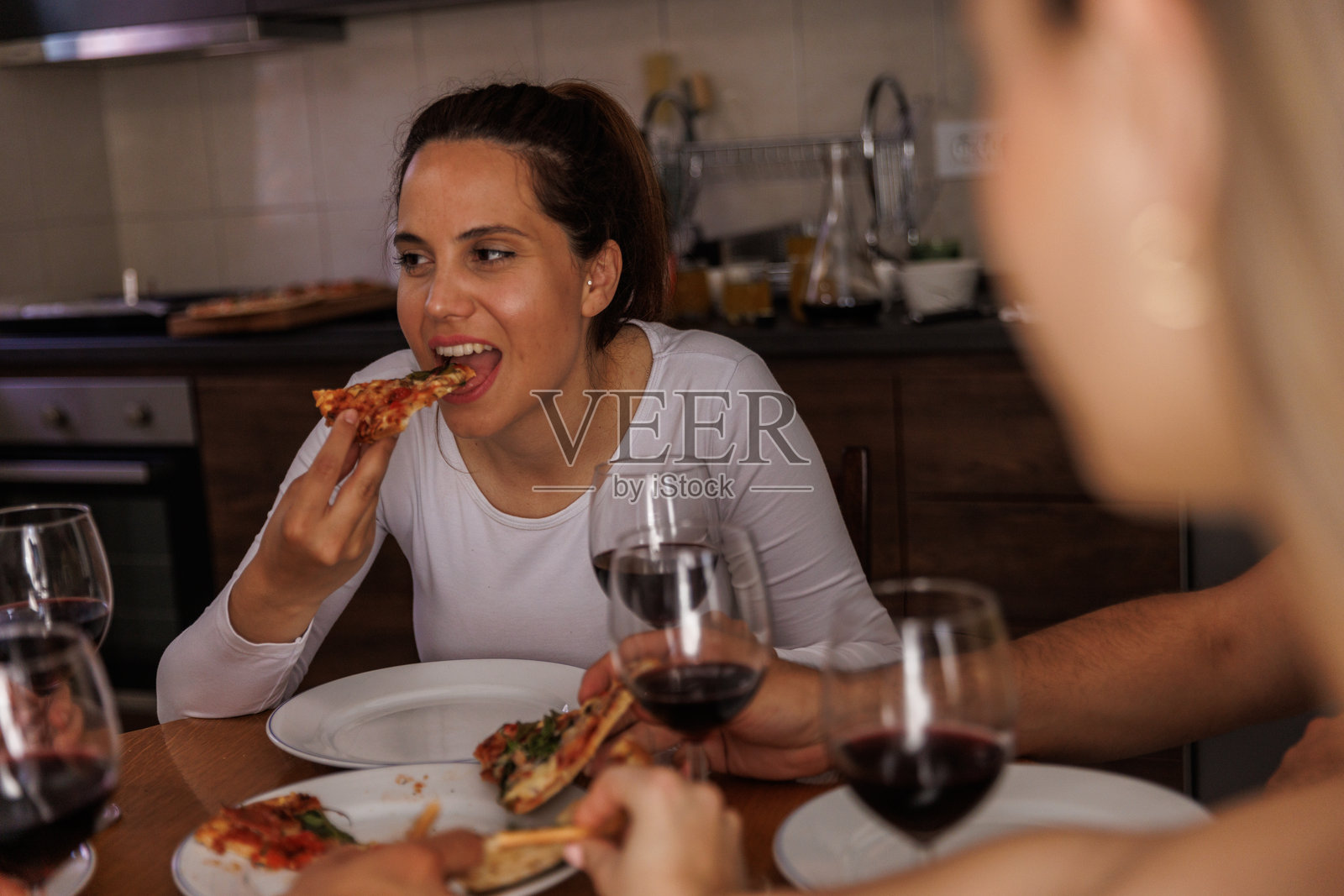 年轻女子与朋友们聚会，一边吃着披萨照片摄影图片