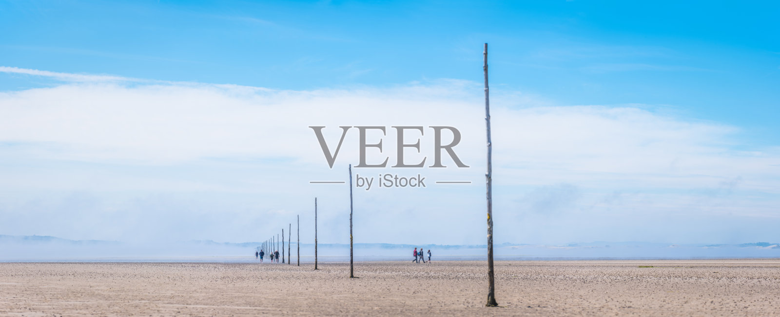 徒步者沿着朝圣者之路穿越林迪斯法恩岛的潮汐平原，北安普敦郡全景照片摄影图片