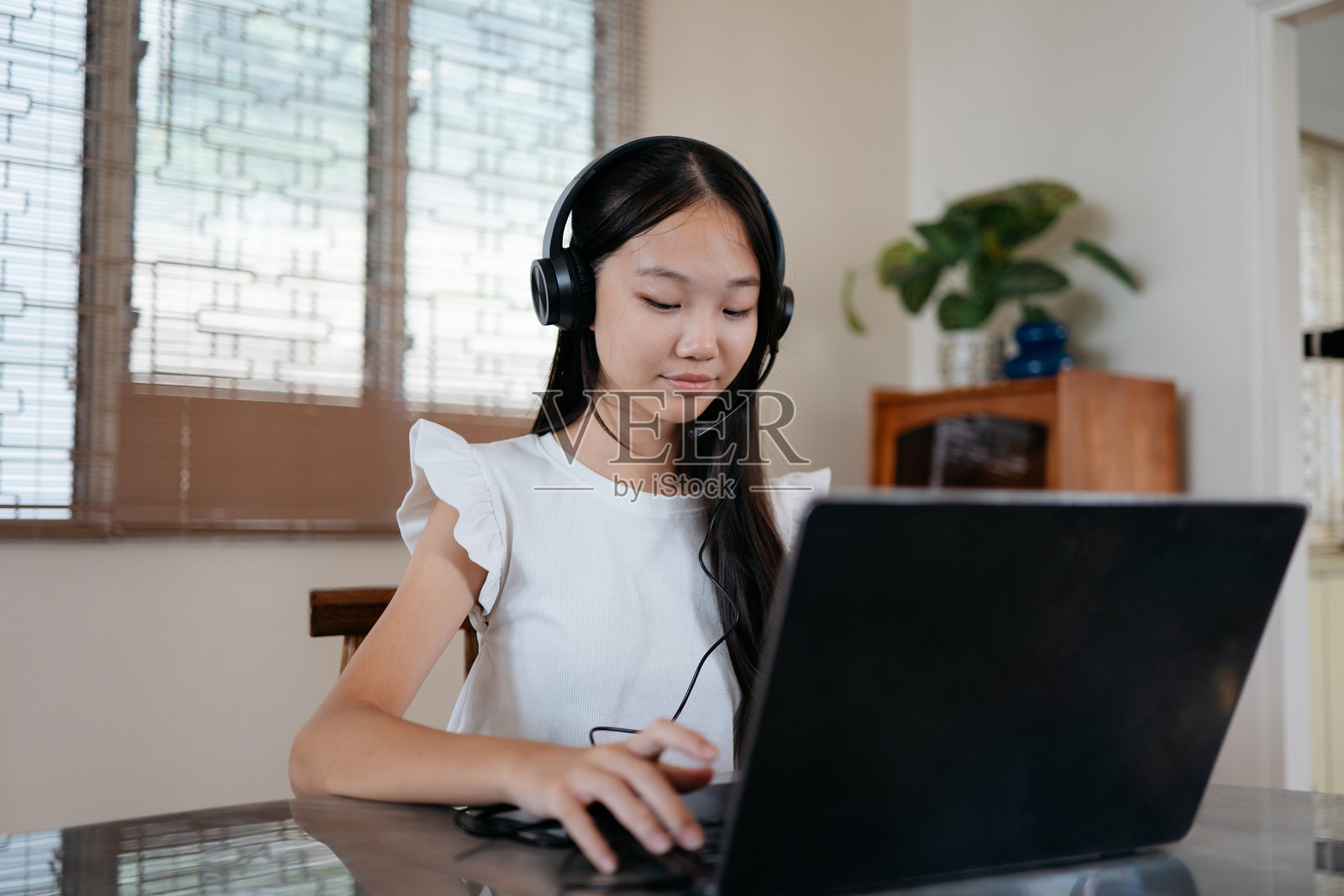 孩子使用笔记本电脑和耳机进行在线交流照片摄影图片