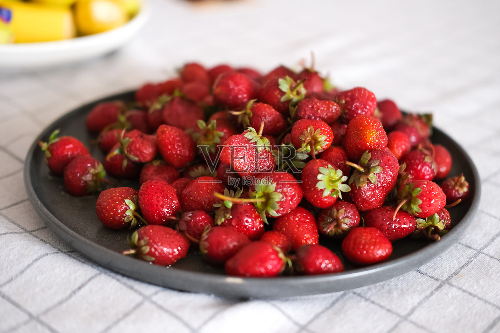 桌子上的盘子里放着新鲜的草莓照片摄影图片