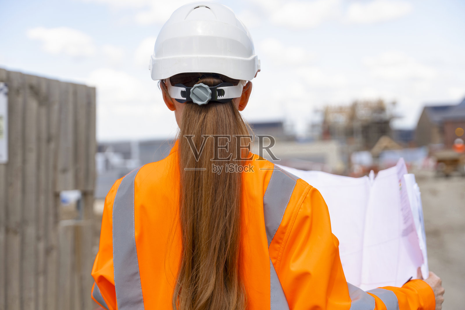 女建筑工人正在建筑工地工作，并对照图纸检查工程进度照片摄影图片