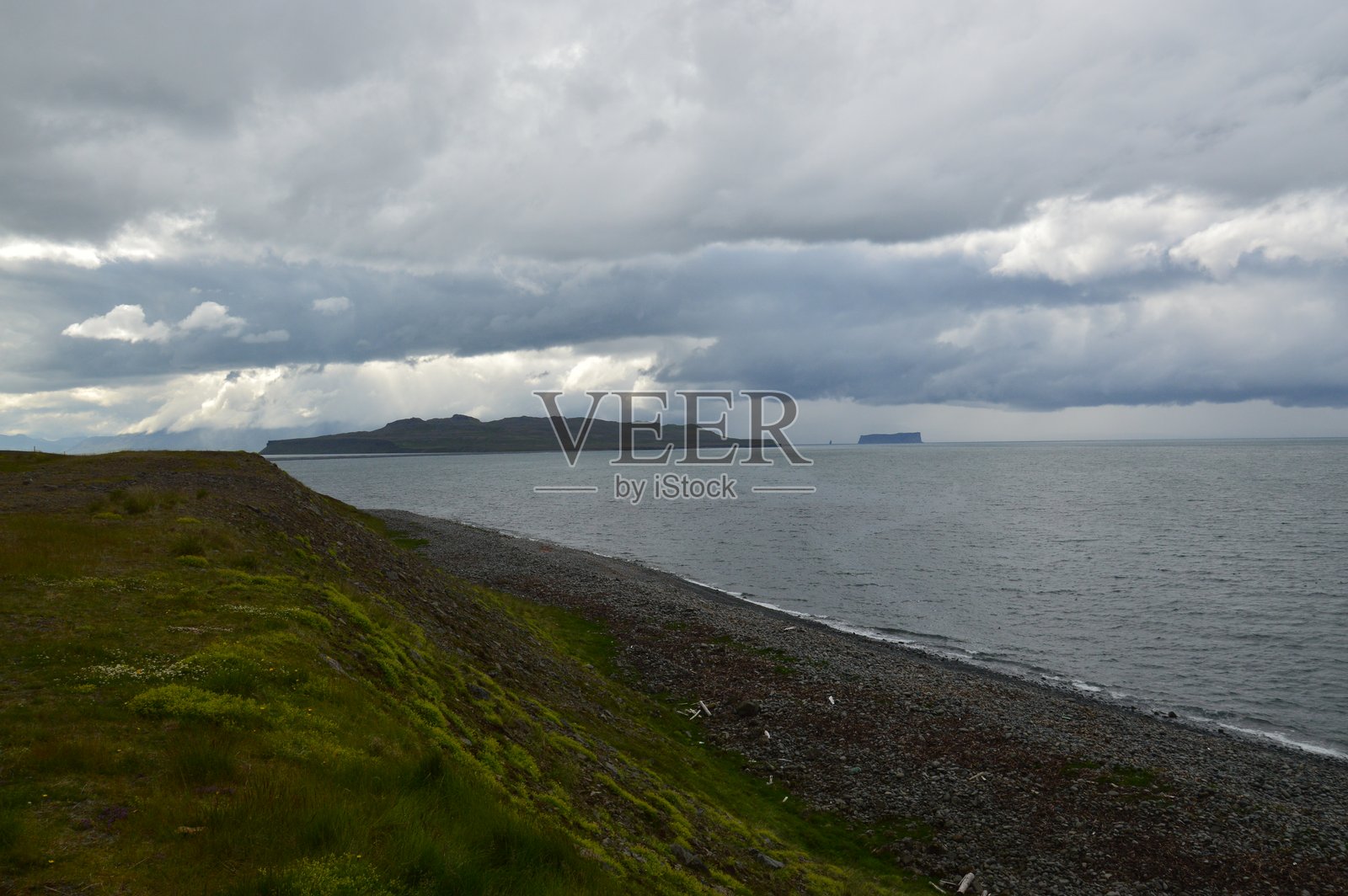 风暴天气下，冰岛戏剧性的鹅卵石海滩和沿海山脉照片摄影图片