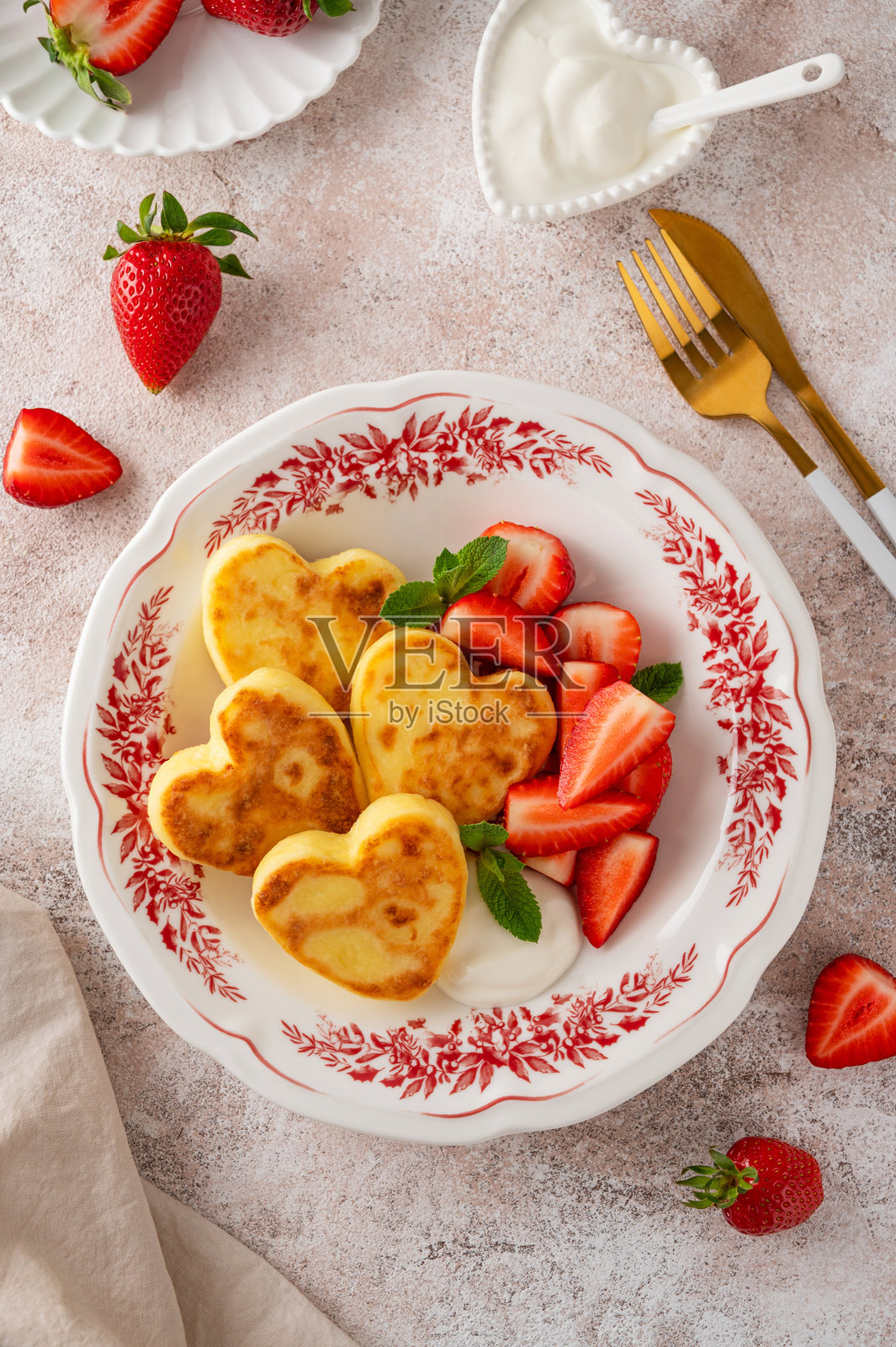 心形奶酪煎饼配酸奶油和新鲜草莓，盛放在盘子里，背景为混凝土。情人节或母亲节的早餐。俯视角度，留有复制空间。照片摄影图片