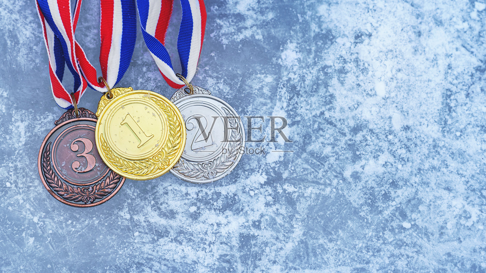 金色、银色和铜质奖牌挂在红色丝带上，孤立地放置在溜冰场上照片摄影图片