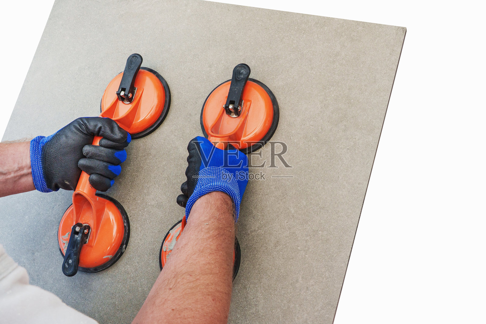 一名建筑工人使用吸盘吊具握着一块陶瓷瓷砖，在纯净的白色背景下，用于瓷砖铺设的概念。照片摄影图片